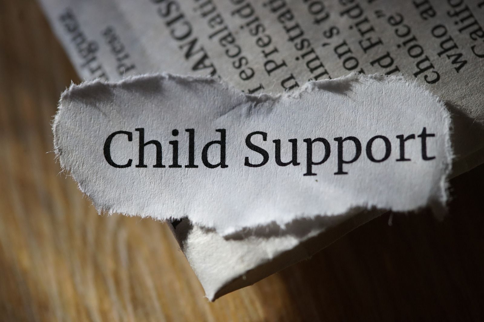 A piece of torn newspaper with the word child support written on it