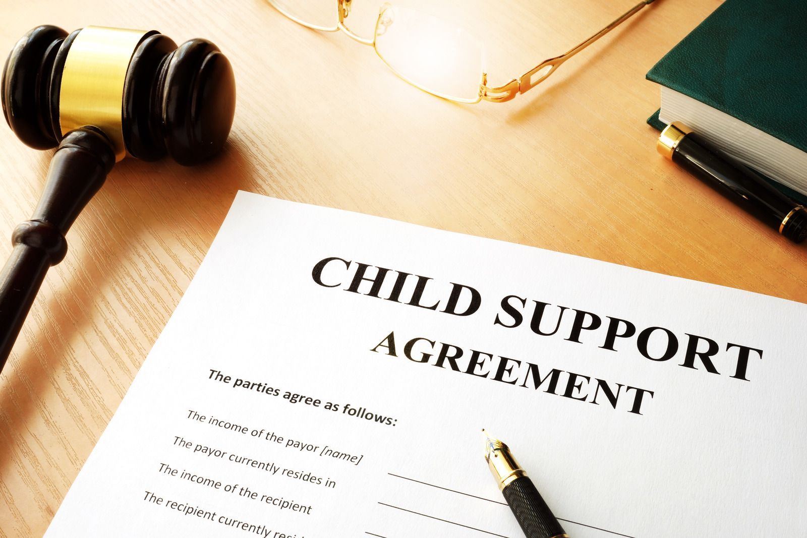 Child Support Agreement on a desk, with a gavel, glasses, and a pen.