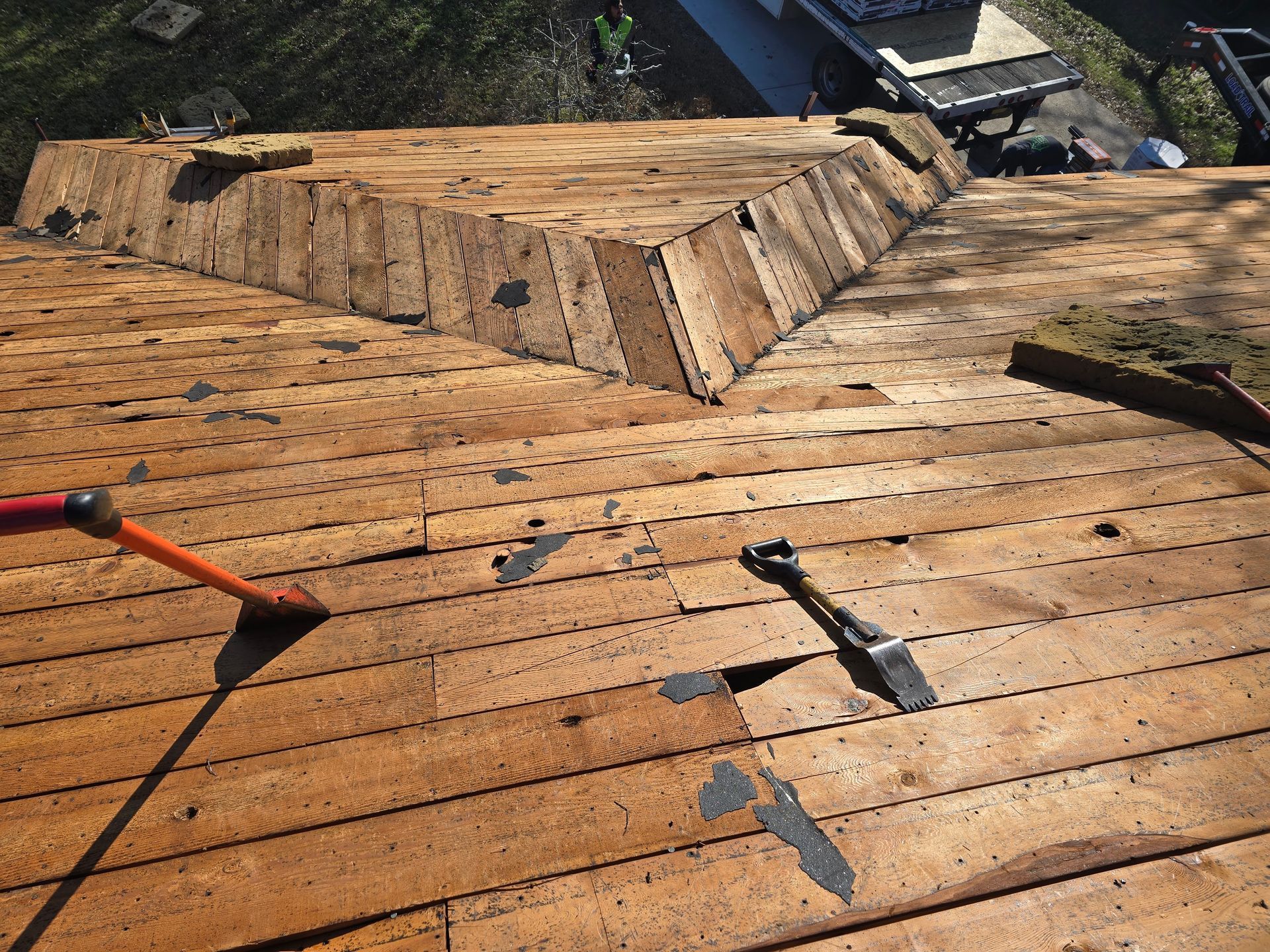 Roof being repaired; wood shingles exposed, tools visible.