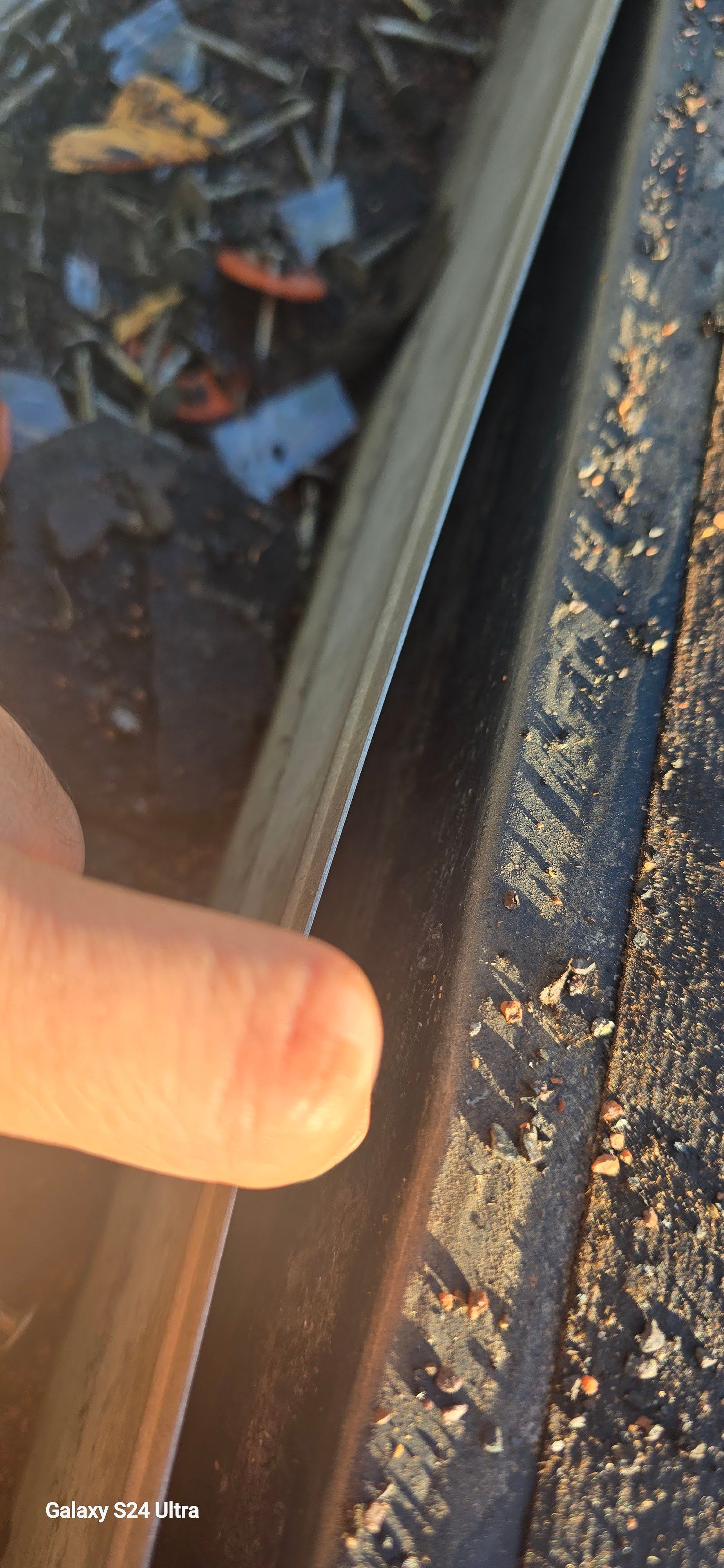 A finger presses against a piece of wood, which is set in a groove with debris.