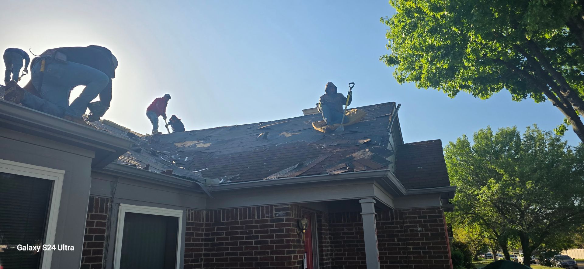 Roofers working on a house roof on a sunny day.