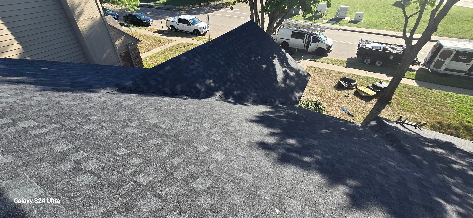 A view from a roof showing a pile of dark gravel and parked vehicles on a street.