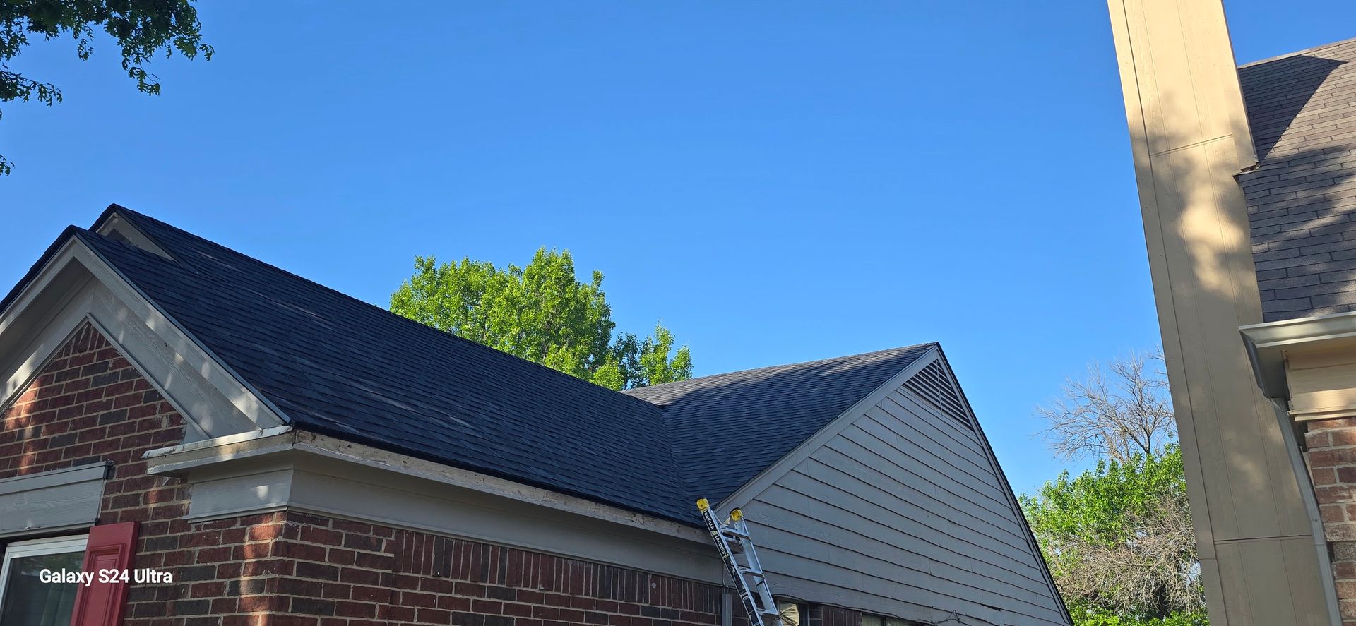 House exterior with a dark roof and brick facade against a blue sky.