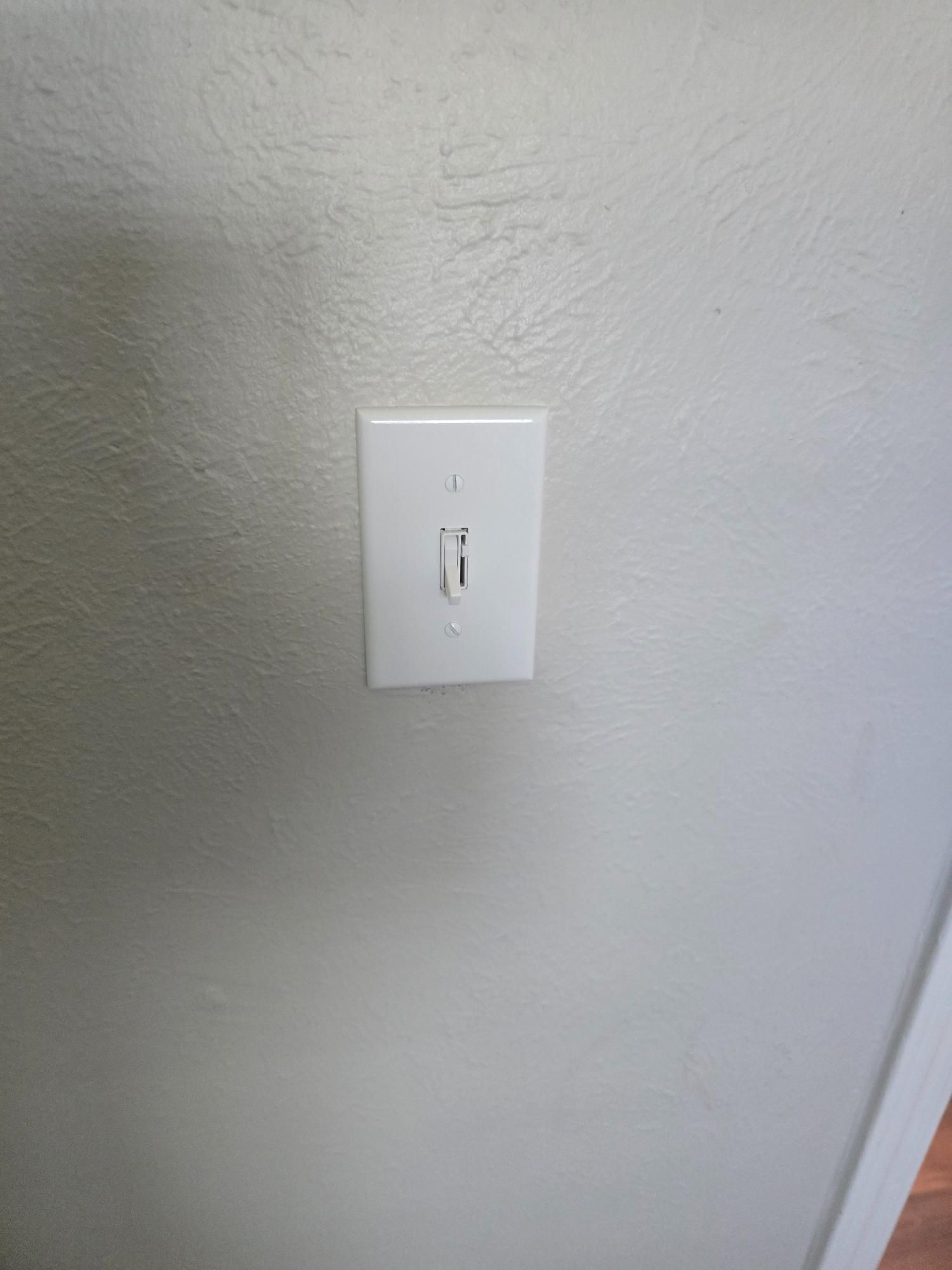 White light switch on a textured gray wall.