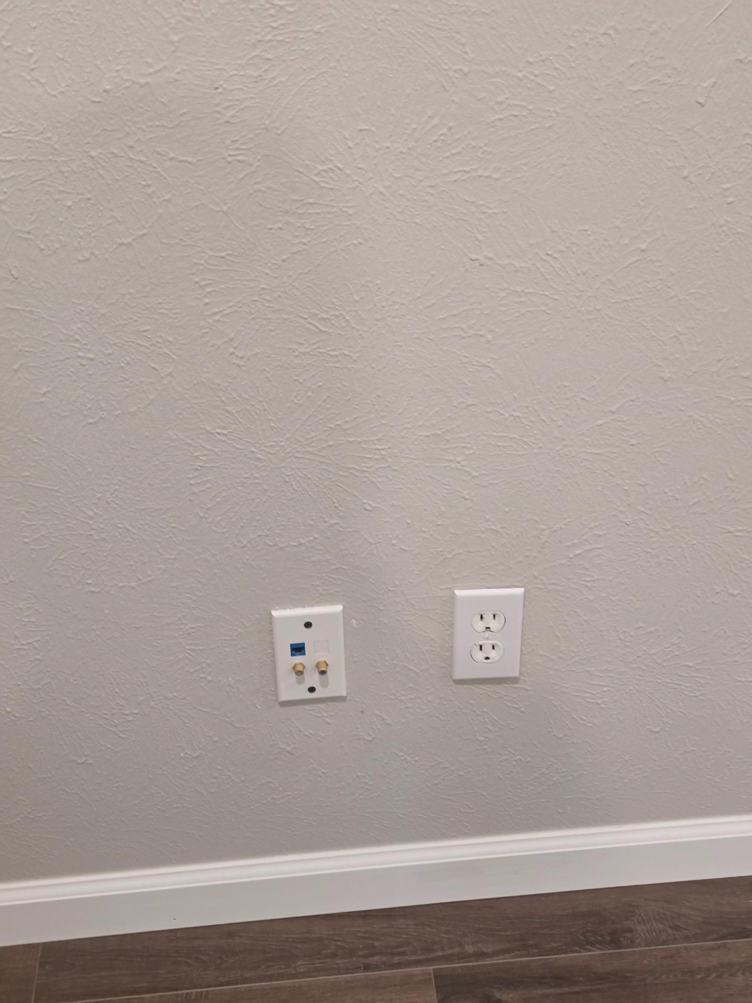 White wall with a TV cable outlet and a power outlet.