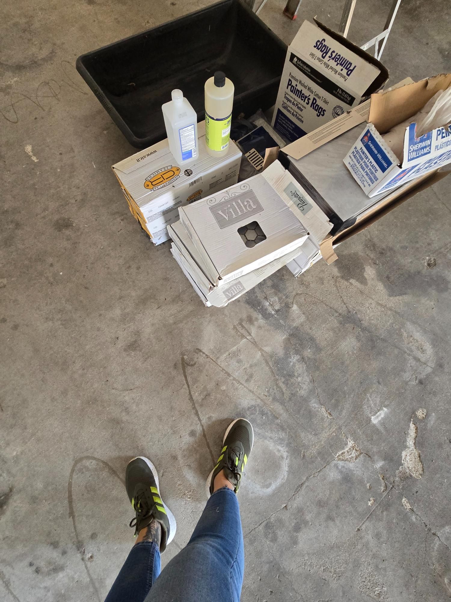 Person standing near construction supplies, gray concrete floor.