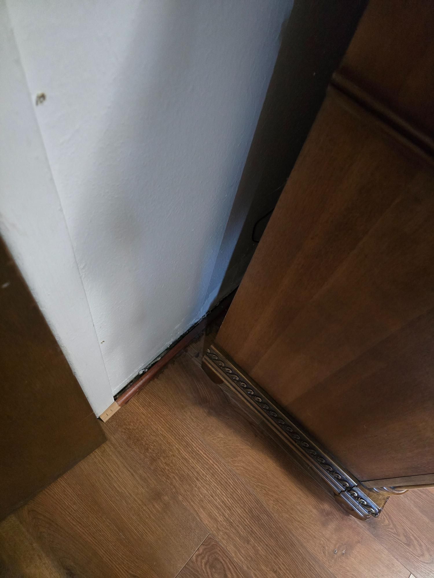 Wooden furniture next to a white wall and wood flooring.