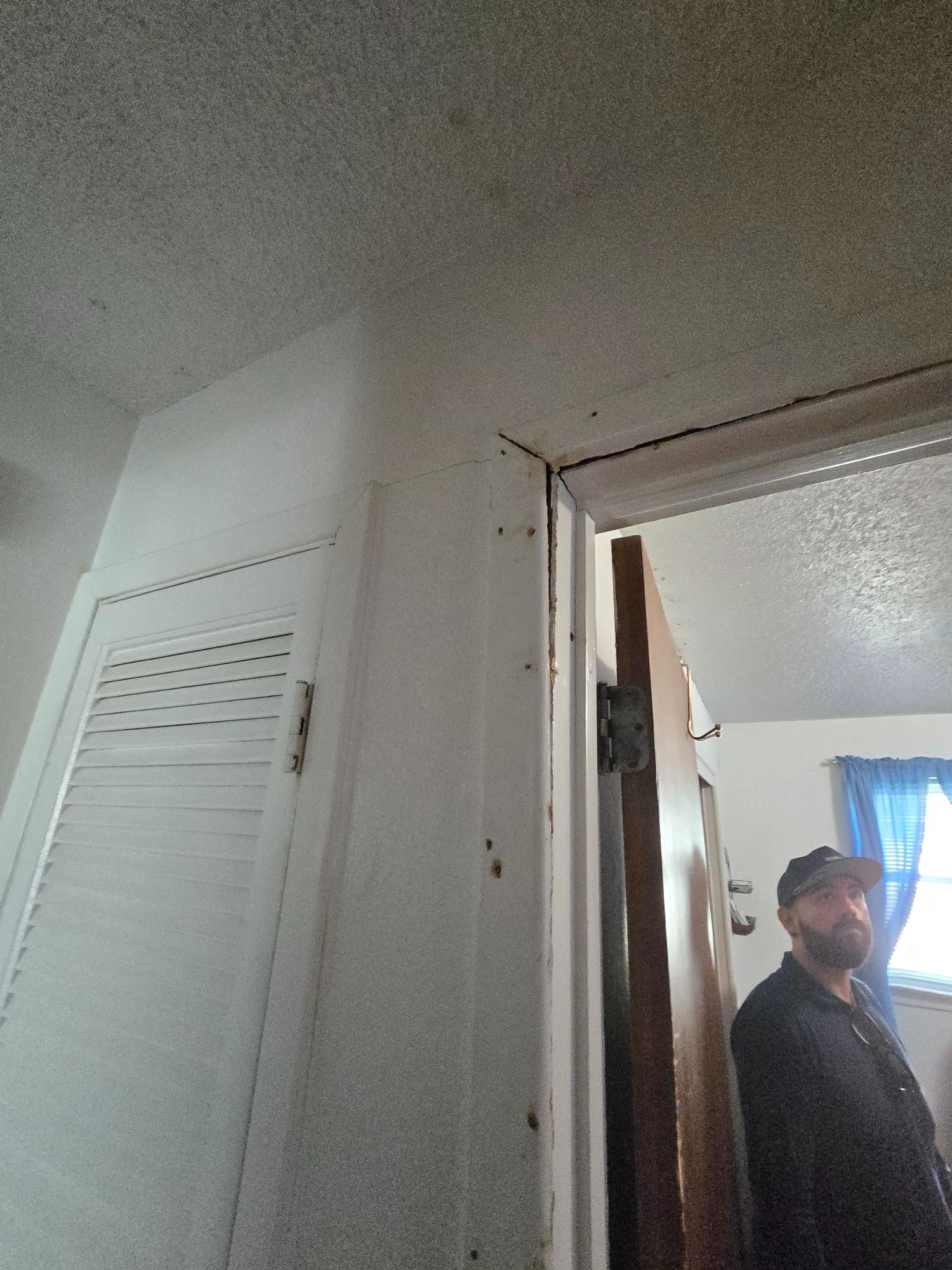 A white closet and doorway, a person stands near the door. White ceiling, gray wall, brown door.