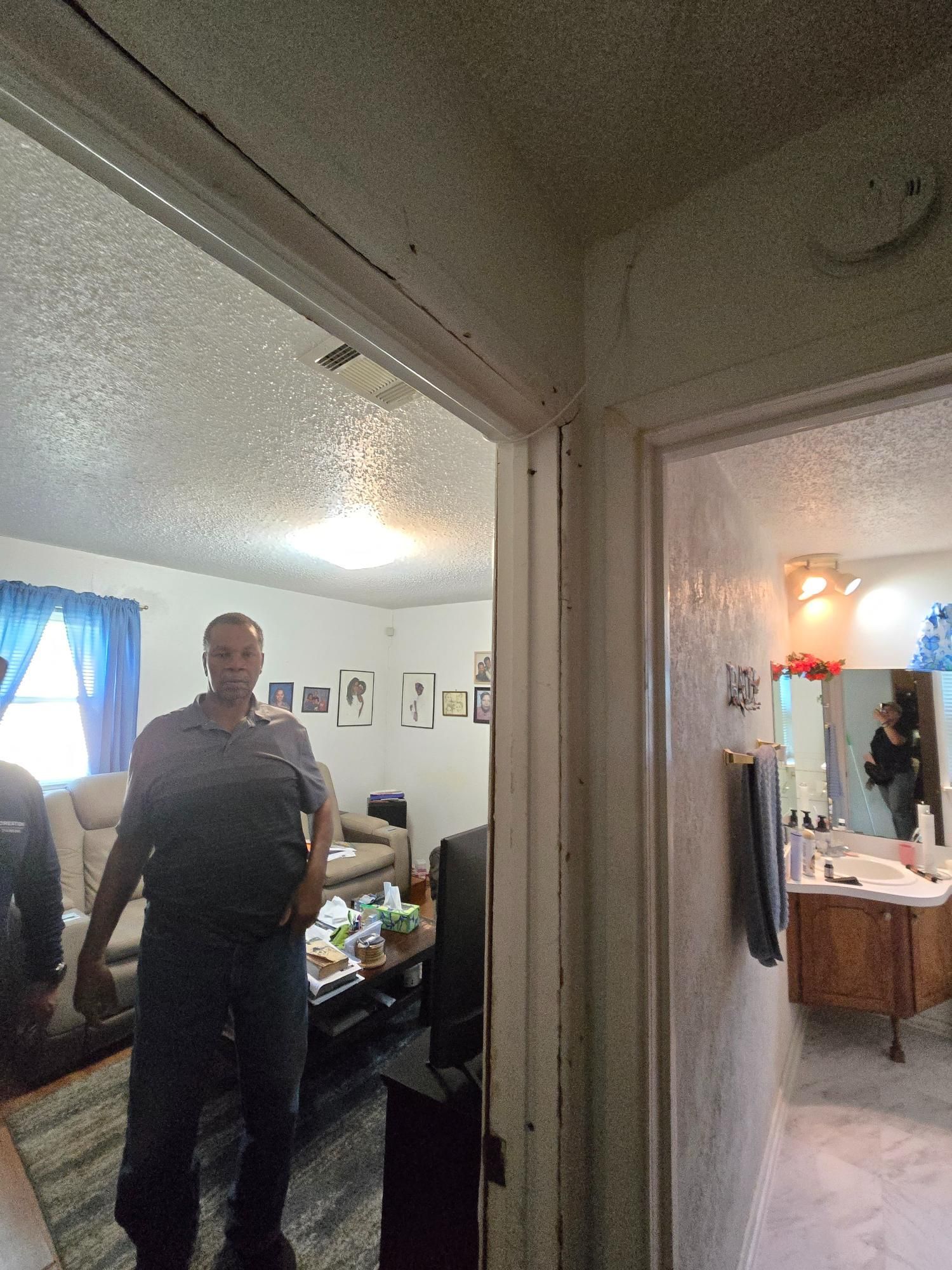 Man standing in doorway, looking forward. Living room and bathroom visible.