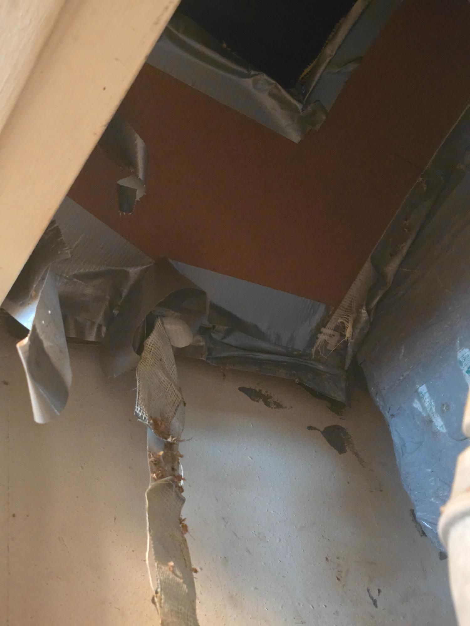 Interior view: Ductwork opening covered with gray tape, visible against an orange-brown background.