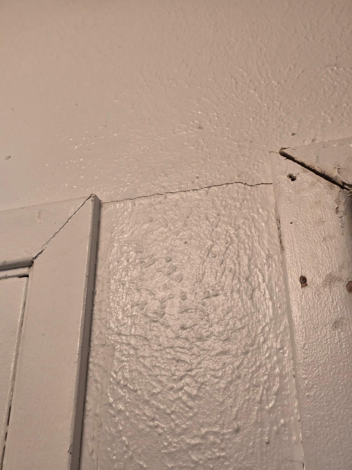 White-painted door frame and ceiling with a crack forming at the corner.