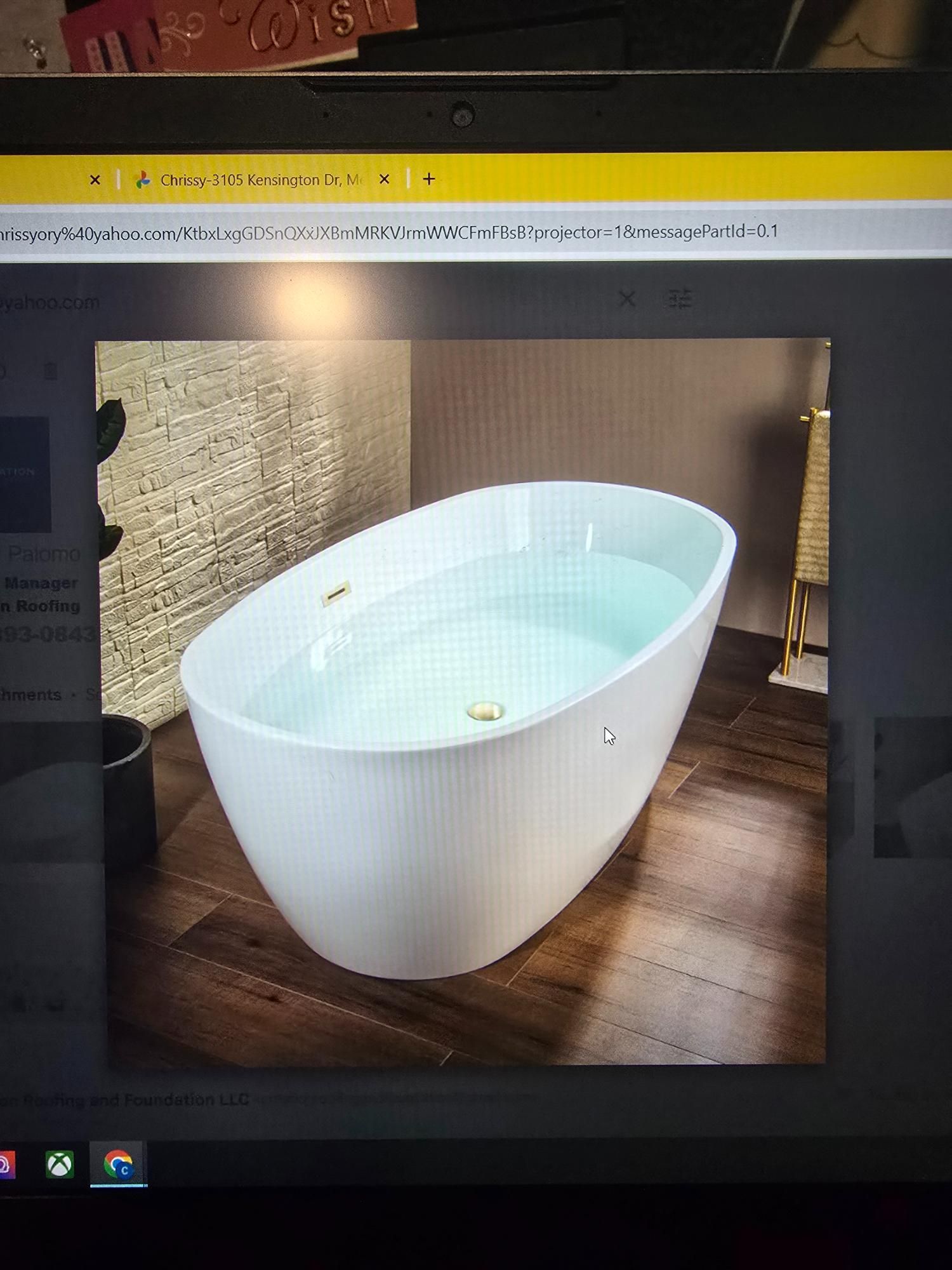 White oval bathtub filled with water in a modern bathroom setting with wood flooring.