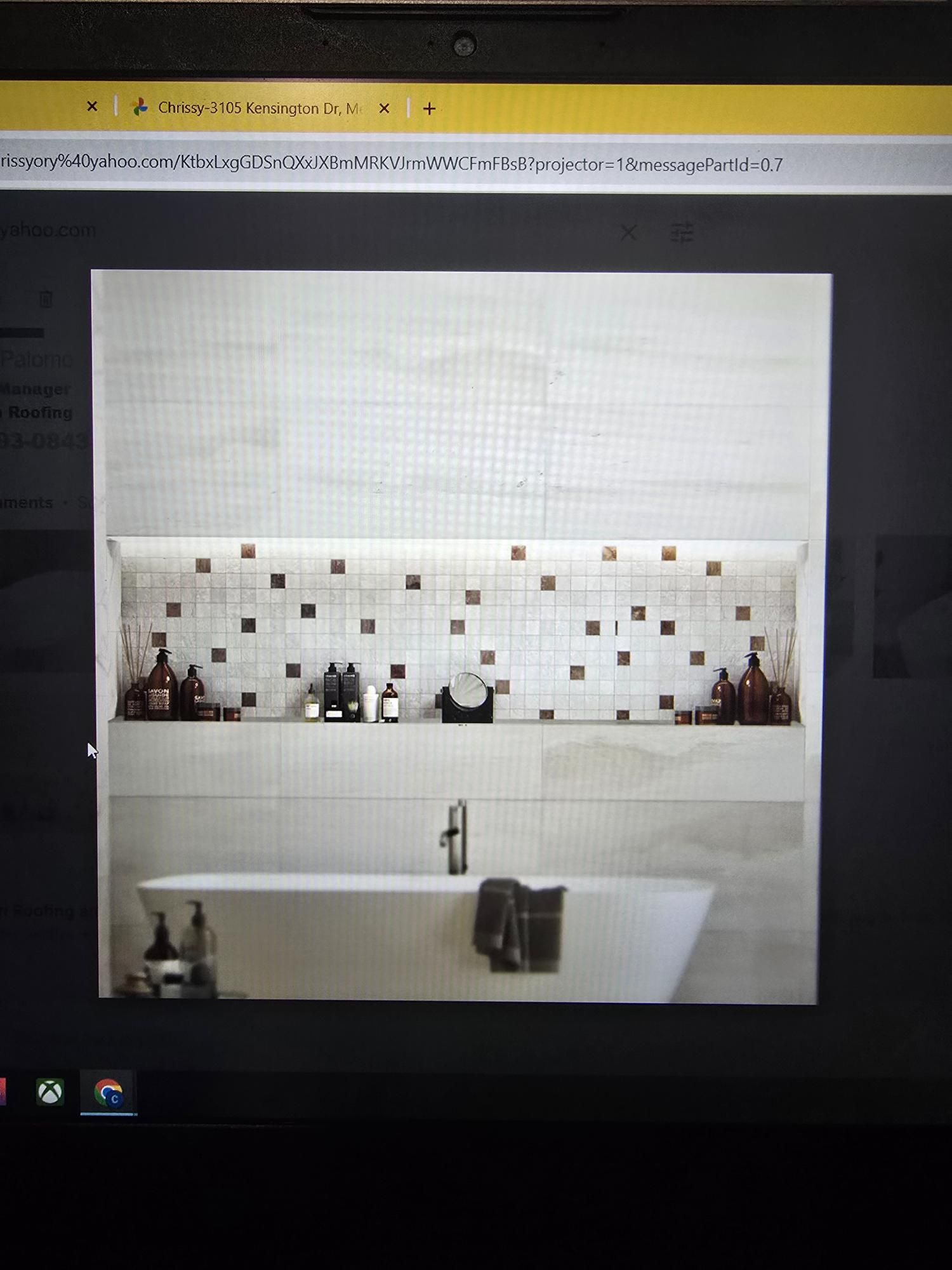 Modern bathroom with a bathtub, shelf with bottles, and mosaic tile accent wall.