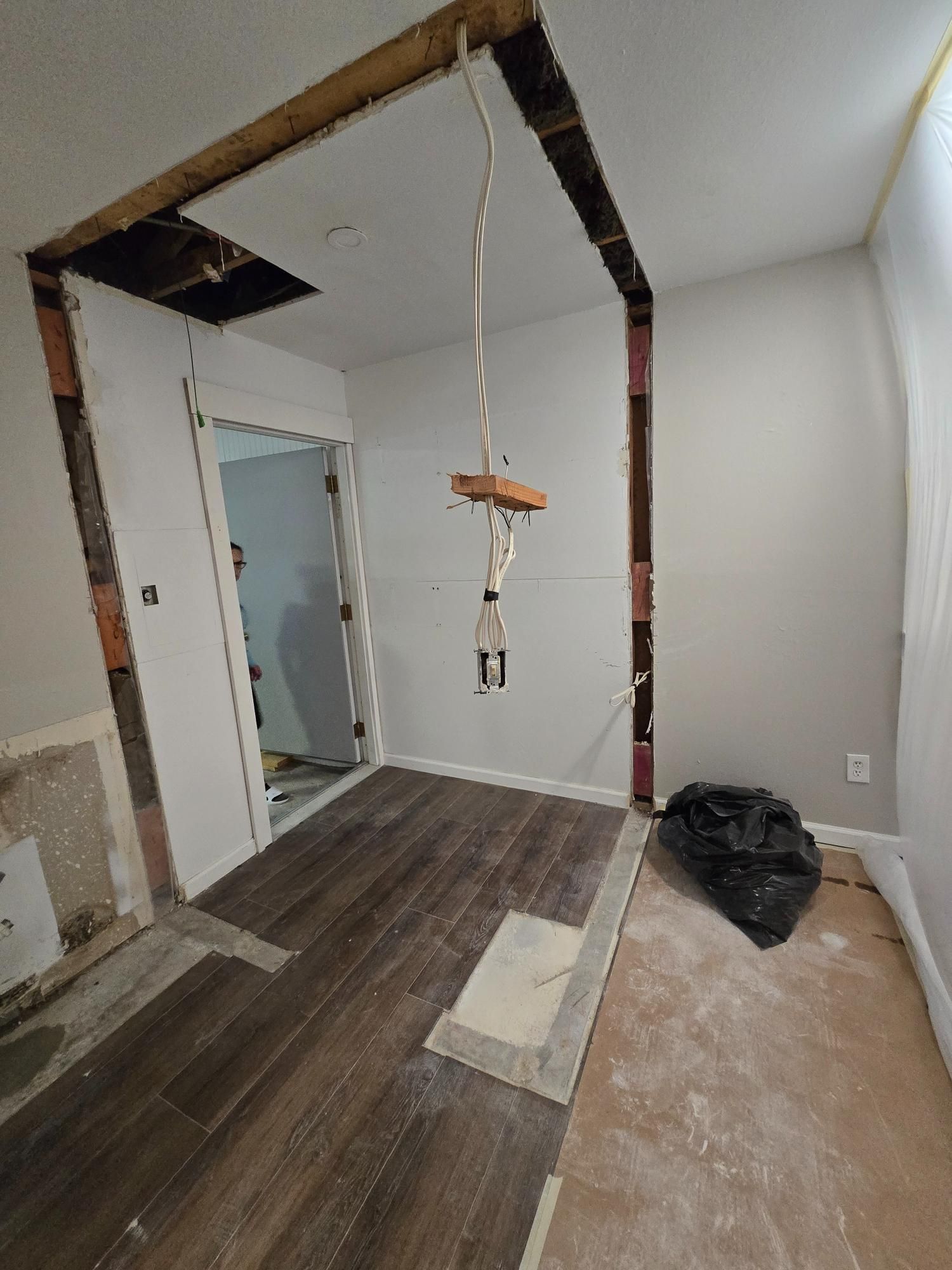 Room under renovation with exposed beams, doorway, and unfinished flooring.