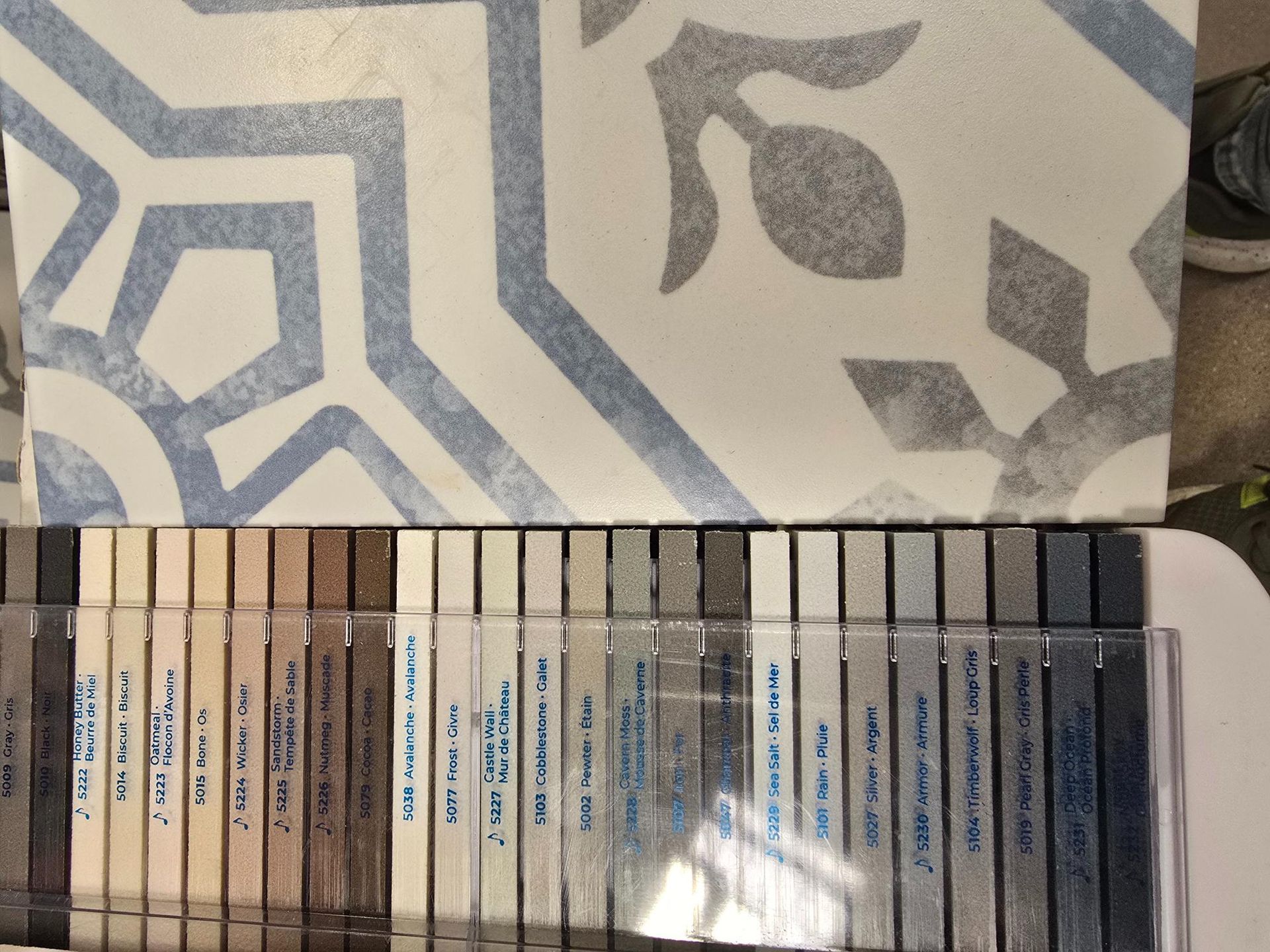 Decorative tile sample with patterned blue and gray design next to a selection of color swatches.