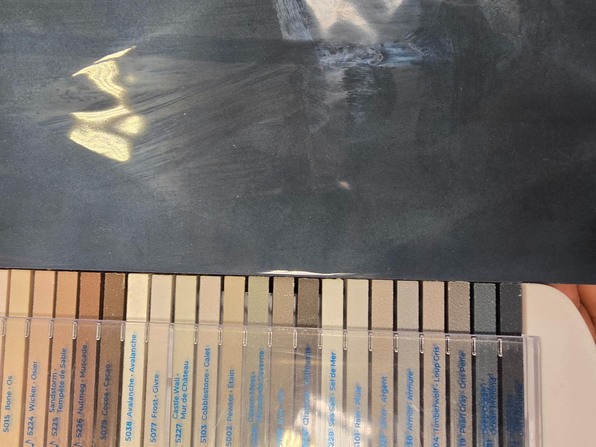 Pastel sticks arranged beneath a dark surface with light reflecting on it.