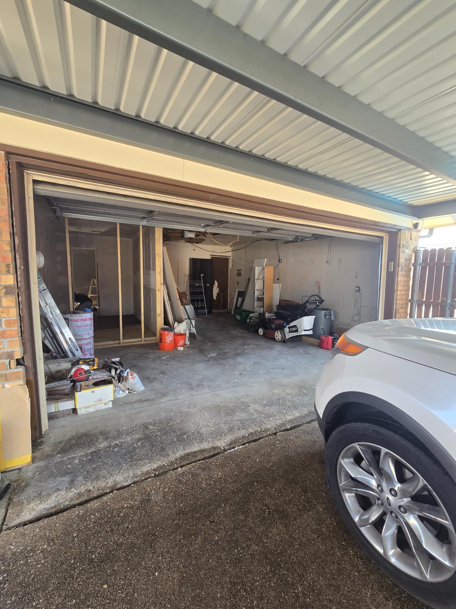Garage conversion in progress, showing a car parked next to the open space with construction materials.
