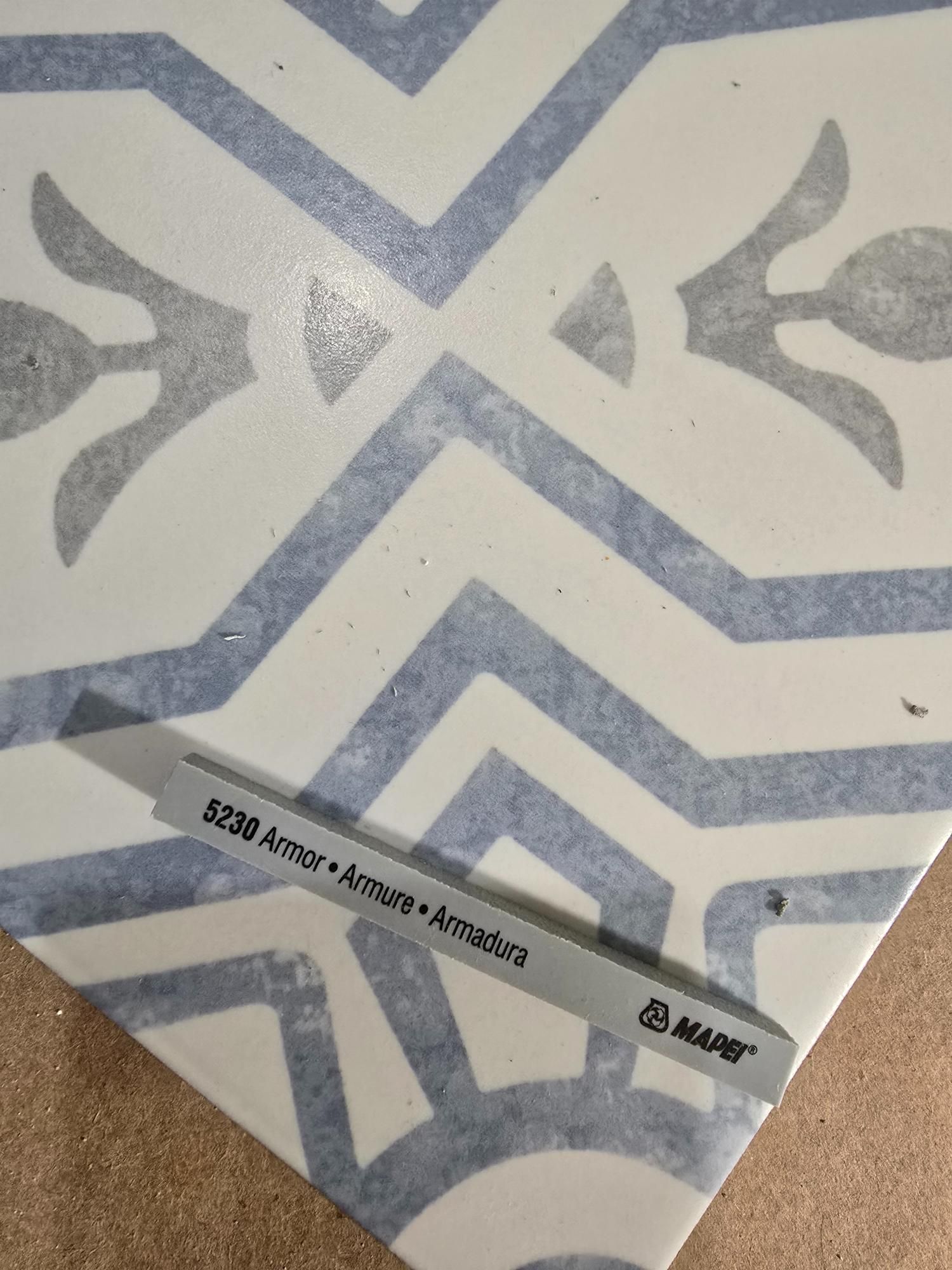 Gray grout tool on patterned tile, blue and white design.