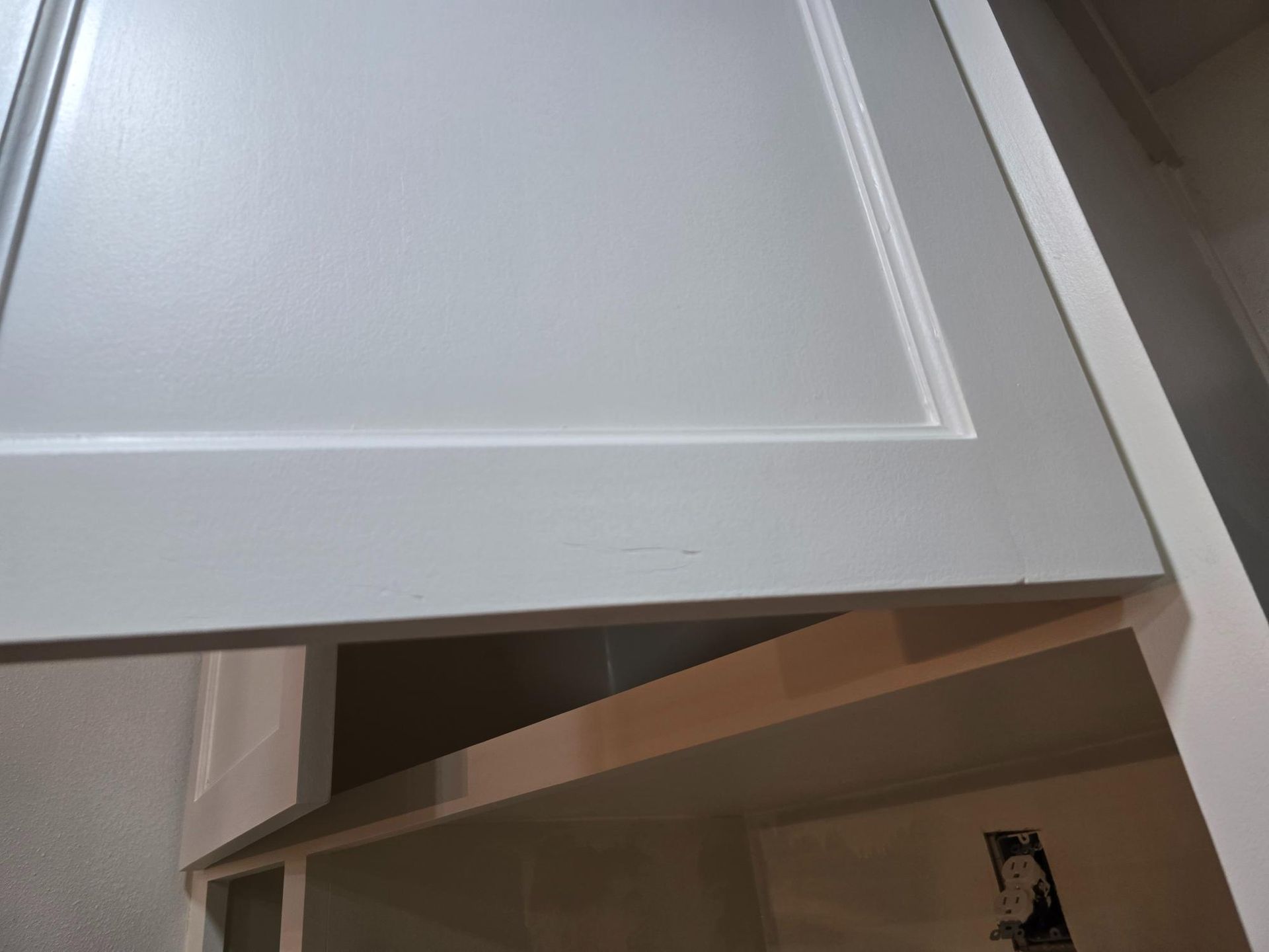 Open gray cabinet door; interior of white shelving unit.