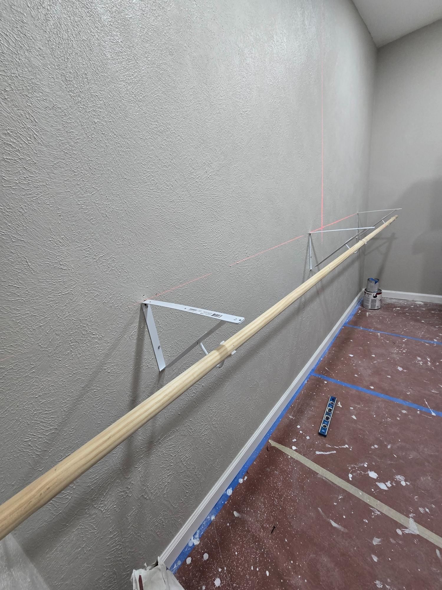 A wooden handrail installed along a staircase with a textured gray wall.
