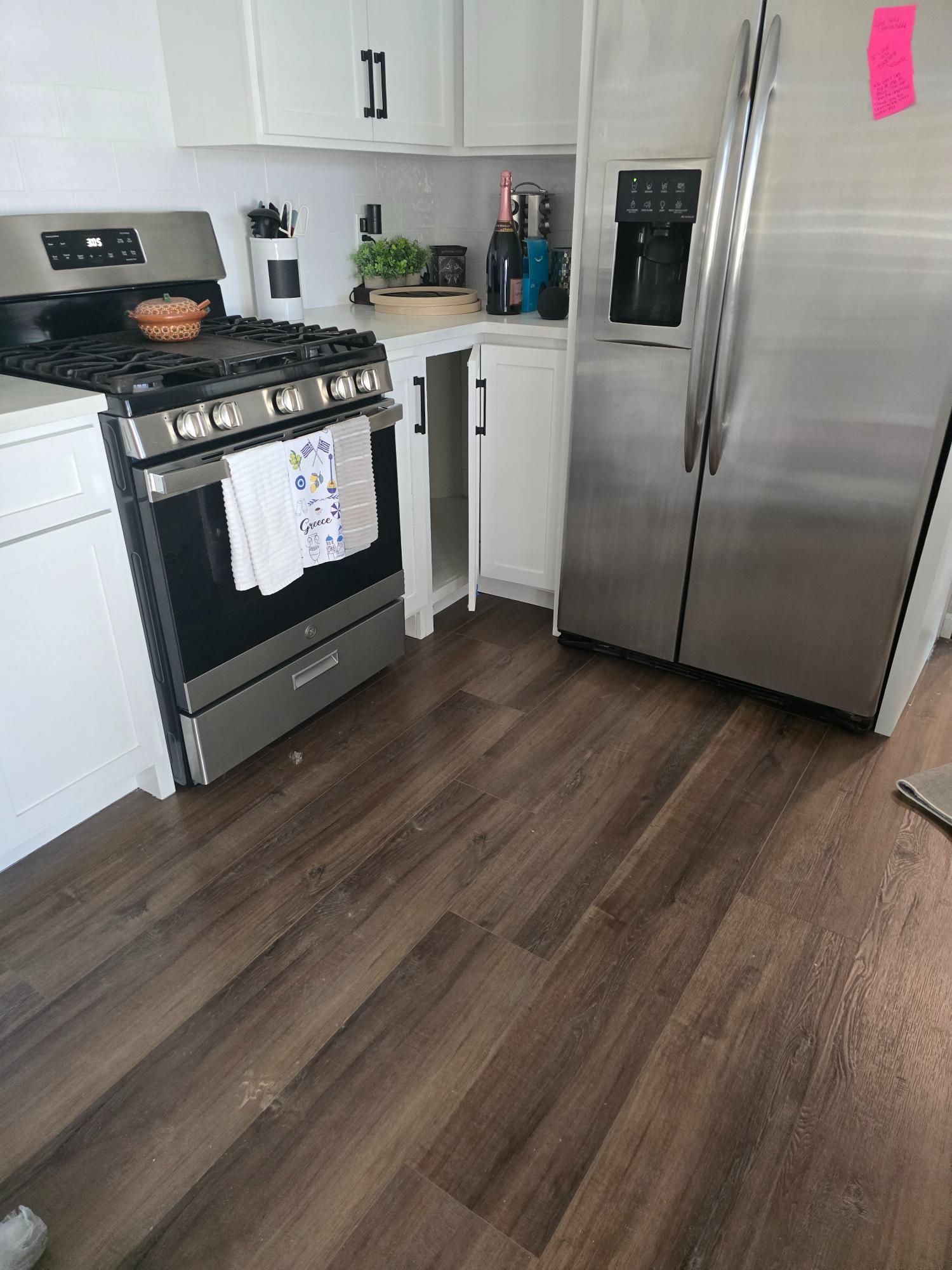 Kitchen with white cabinets, stainless steel appliances, and wood-look flooring.