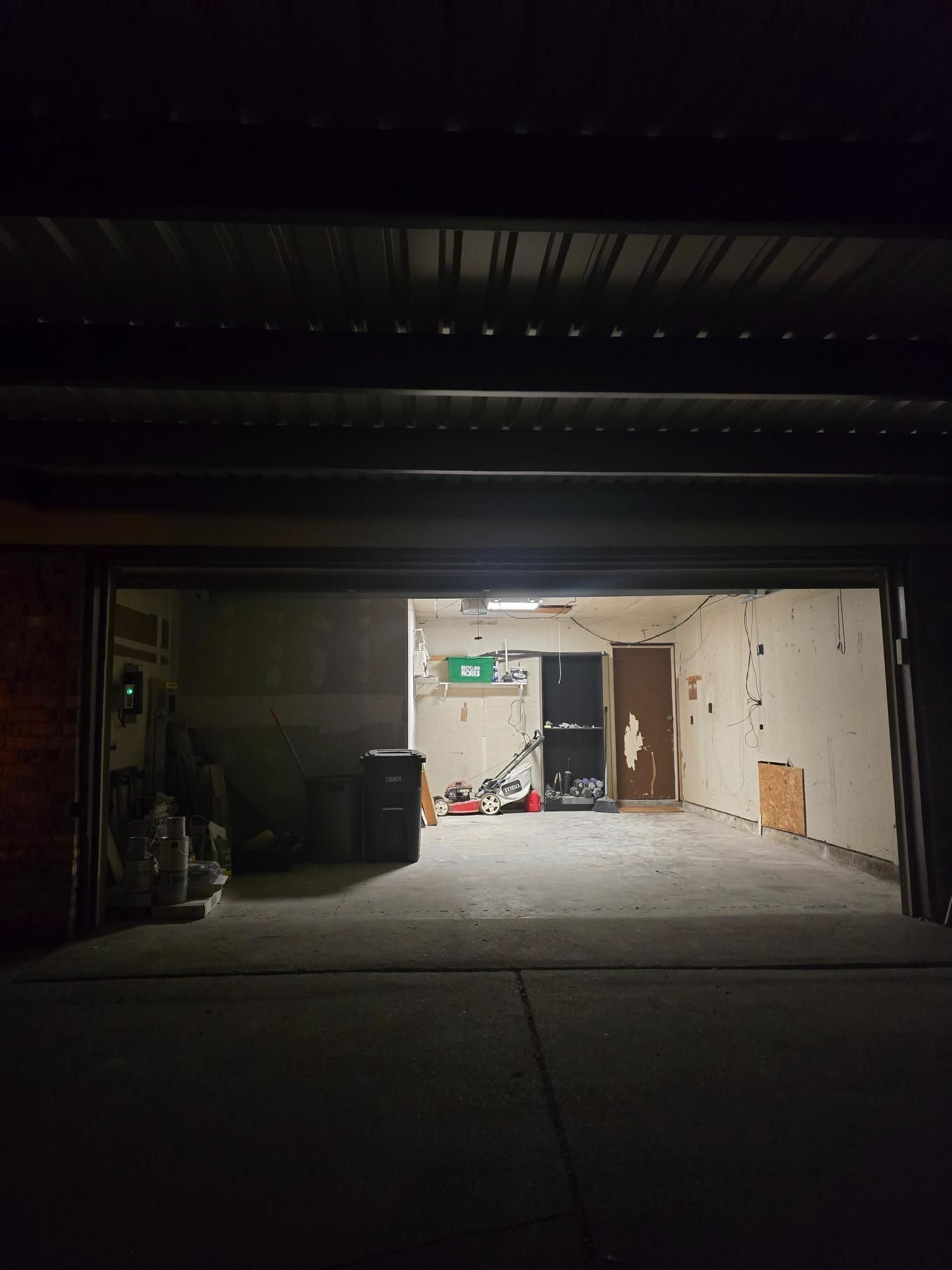 View from dark garage into a brightly lit interior space with concrete floor and exposed walls.