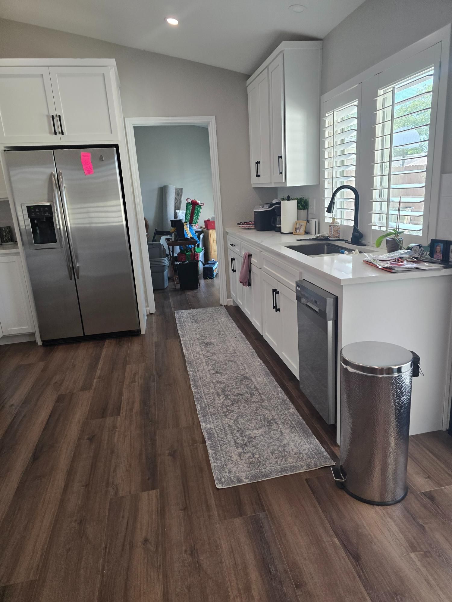 Kitchen with white cabinets, stainless steel refrigerator, and dark wood-look flooring.