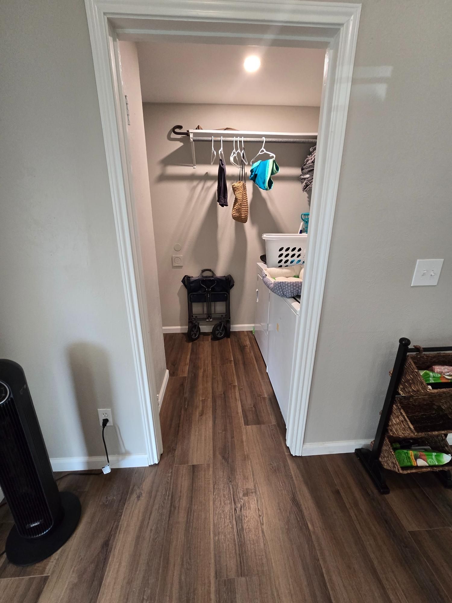 Laundry room entry with wood-look flooring, gray walls, open doorway, and a fan.