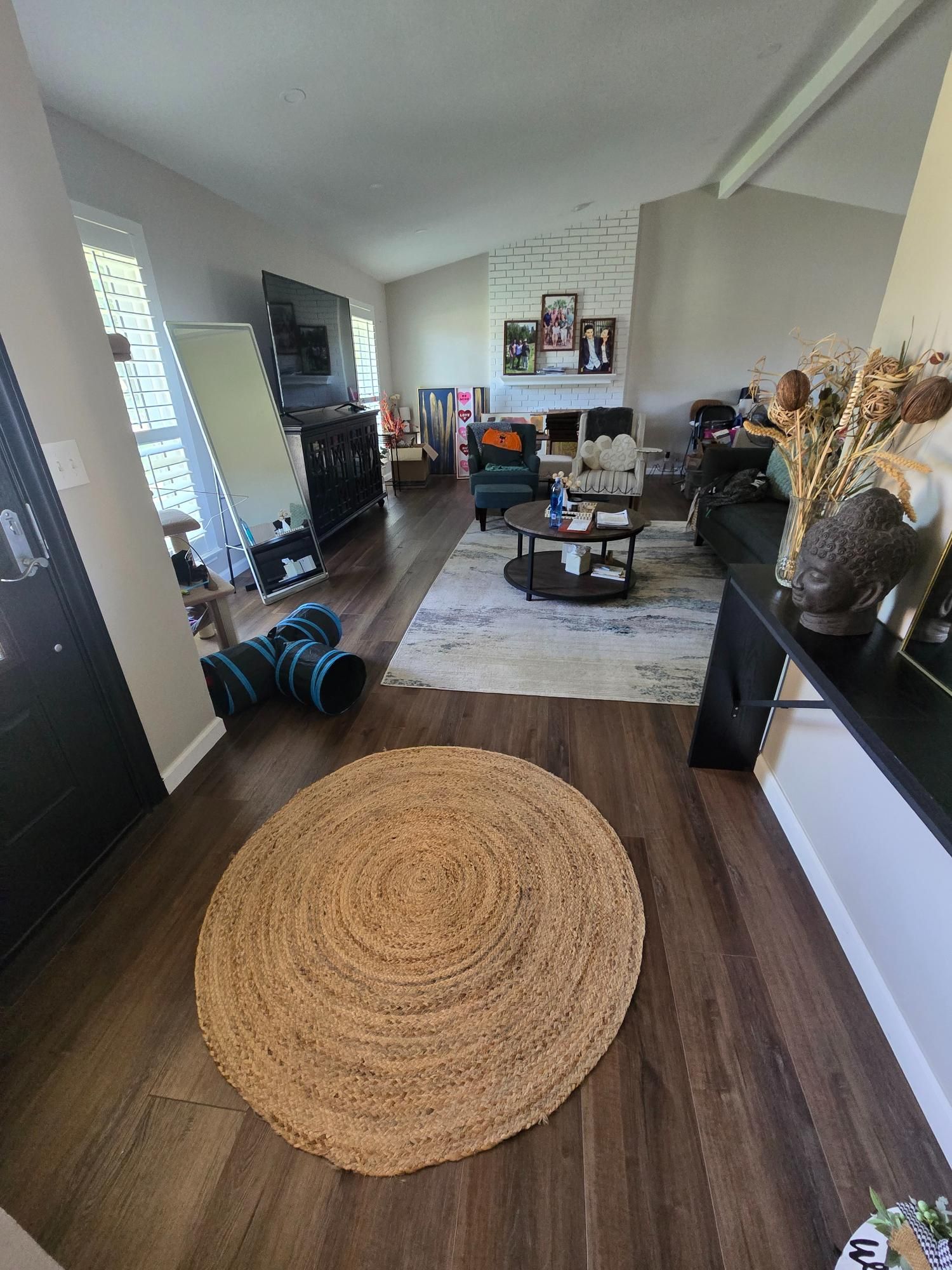 Living room with a large round jute rug and dark wood floors.
