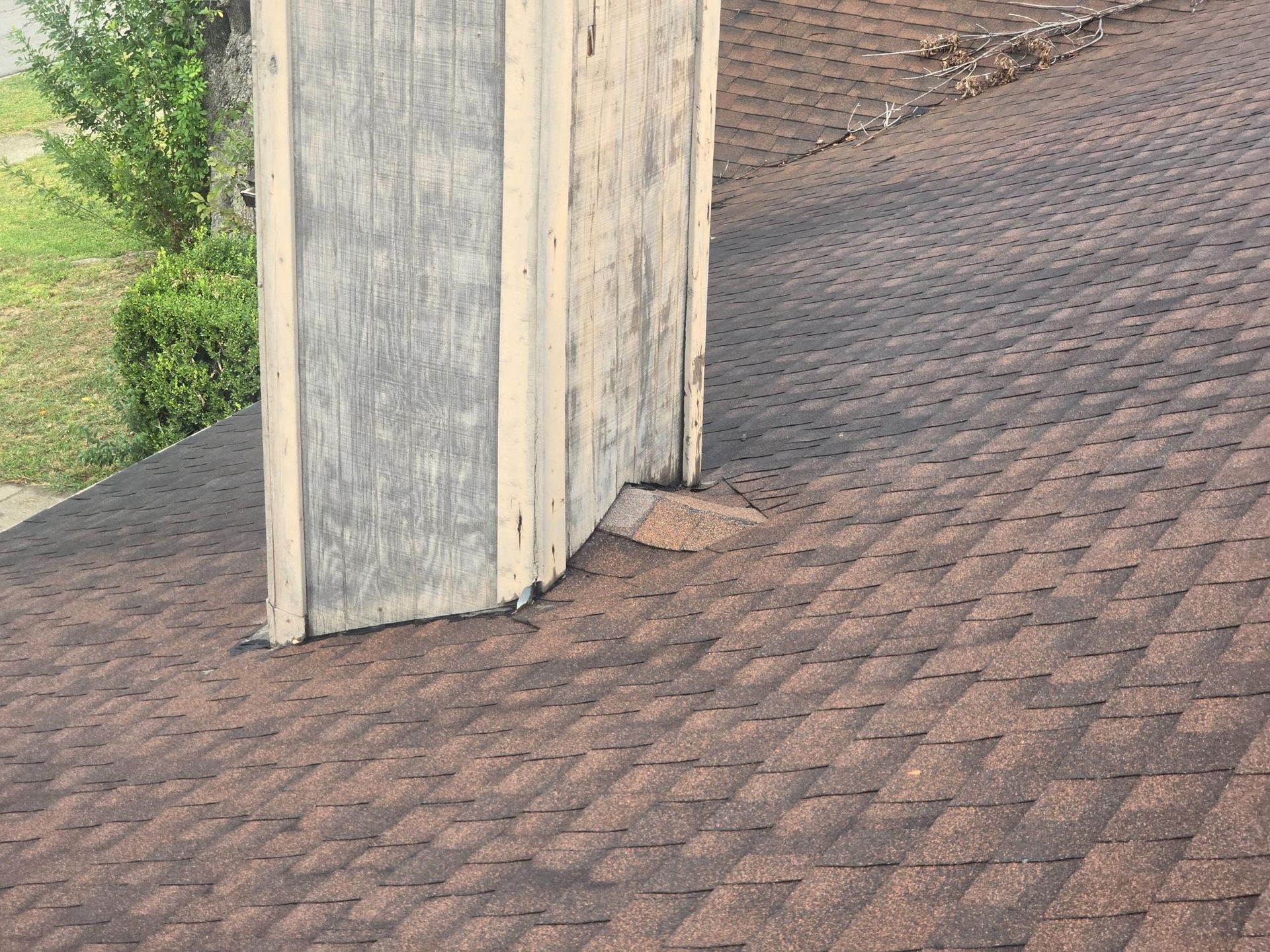 Brown shingle roof with a weathered, wooden chimney protruding.