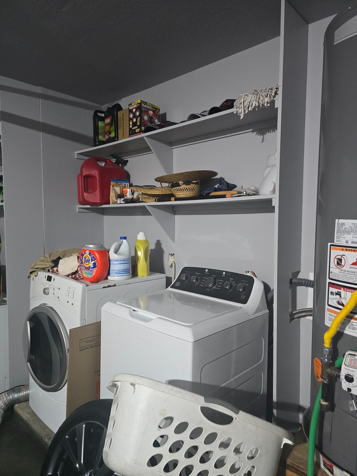 Laundry room with a washing machine, dryer, shelves, and a laundry basket.
