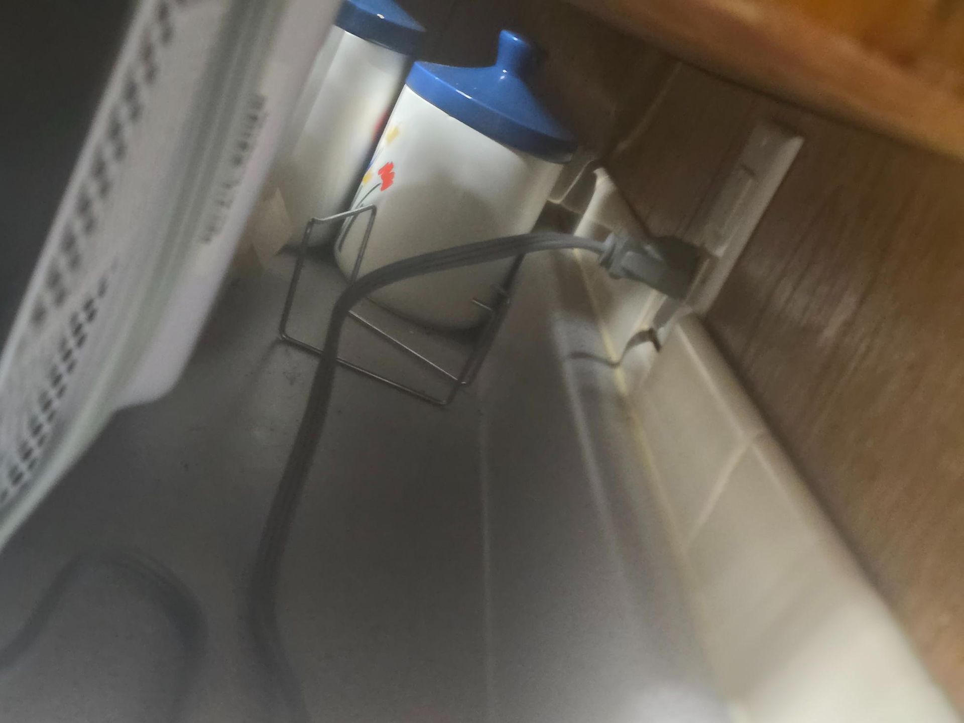 View inside a cabinet with a power outlet, containers, and a metal rack.