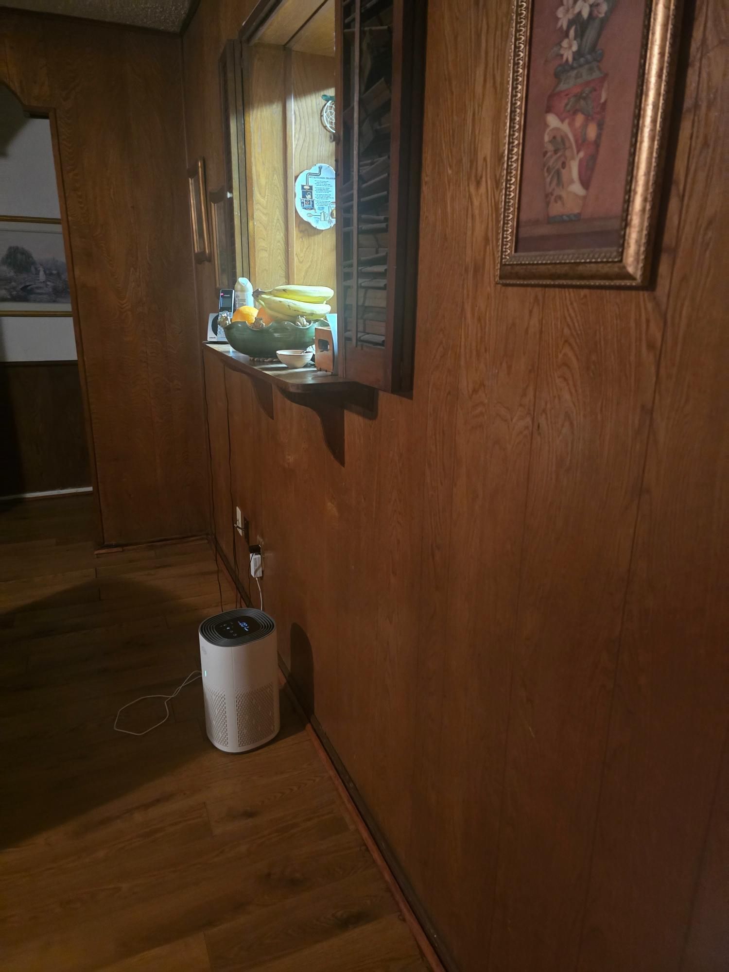 Hallway with wooden paneling, a small window, and a white air purifier on the floor.
