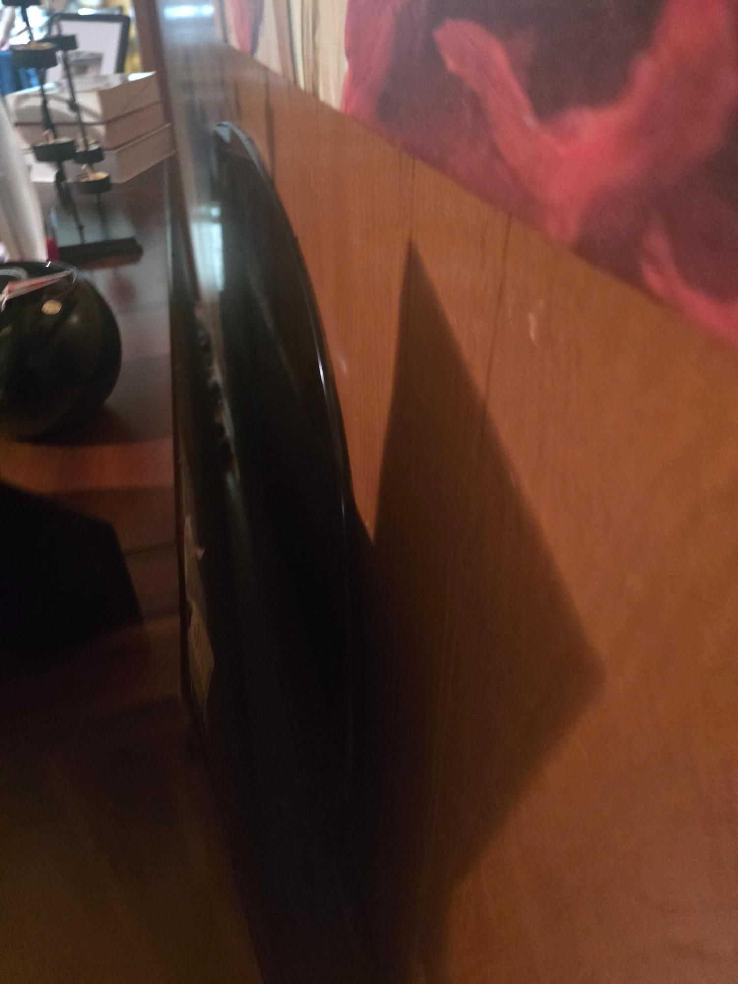 Black guitar leaning against a brown wall, casting a shadow.