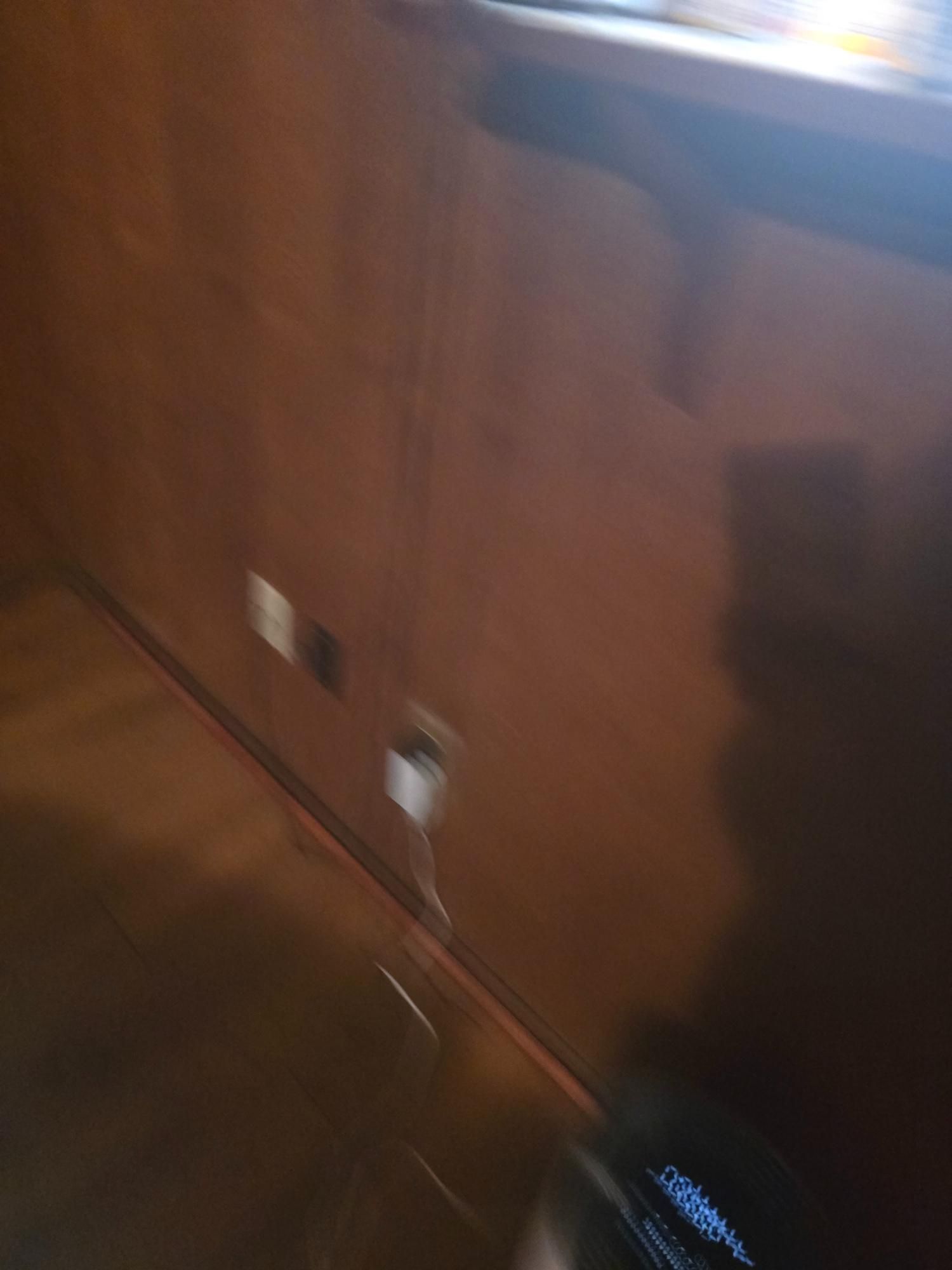 Brown paneled wall with electrical outlets and a cord plugged in.