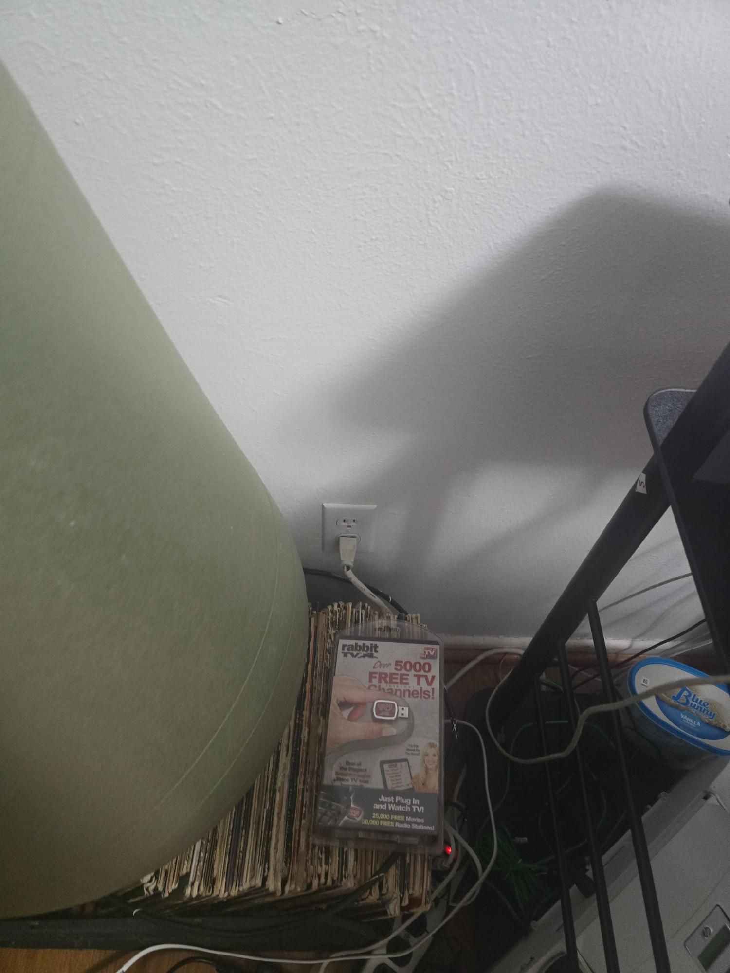 White ceiling with electrical outlet, wires, and a poster under a curved wall.
