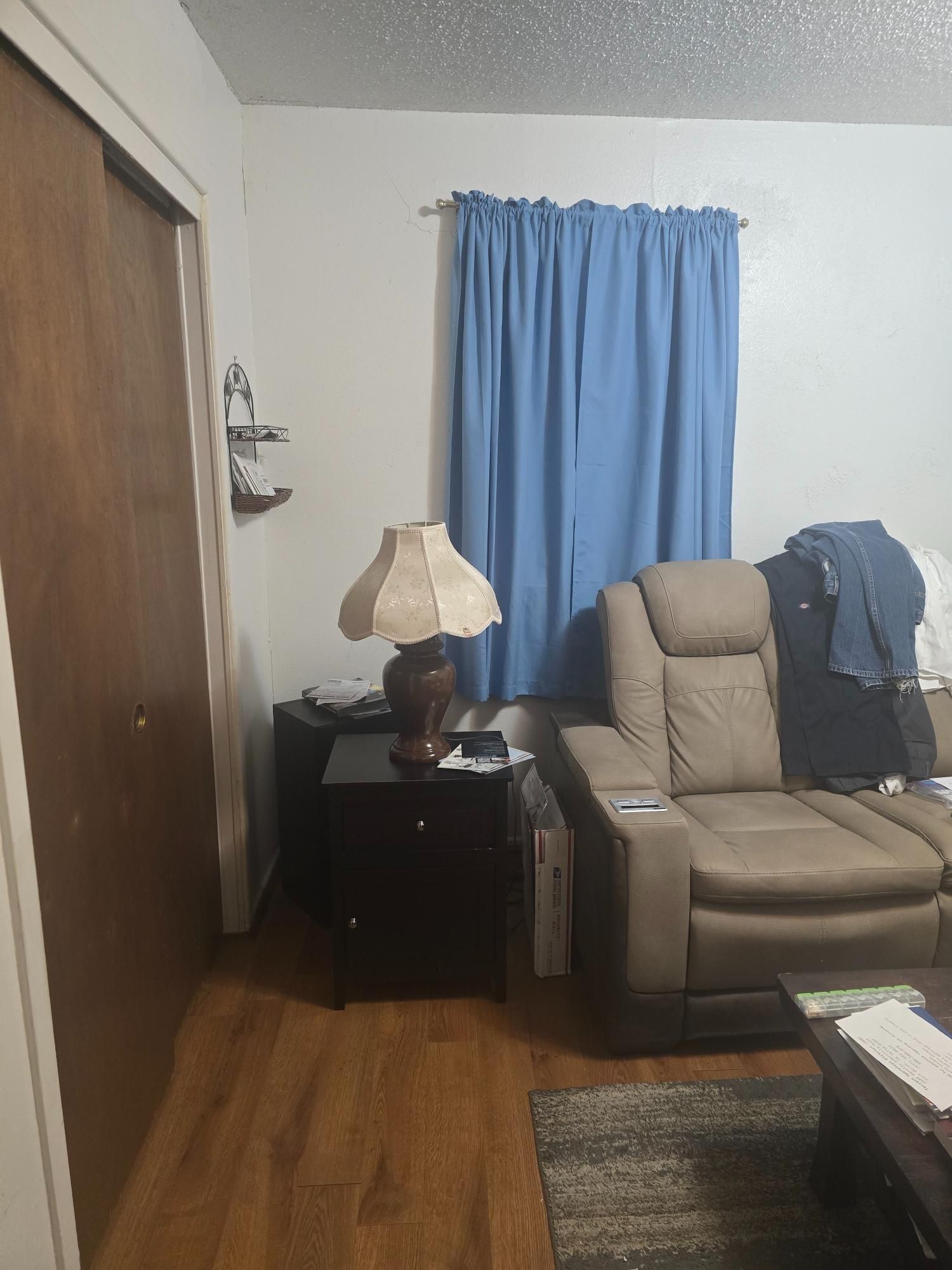 Living room with brown recliner, dark nightstand, and blue curtains.