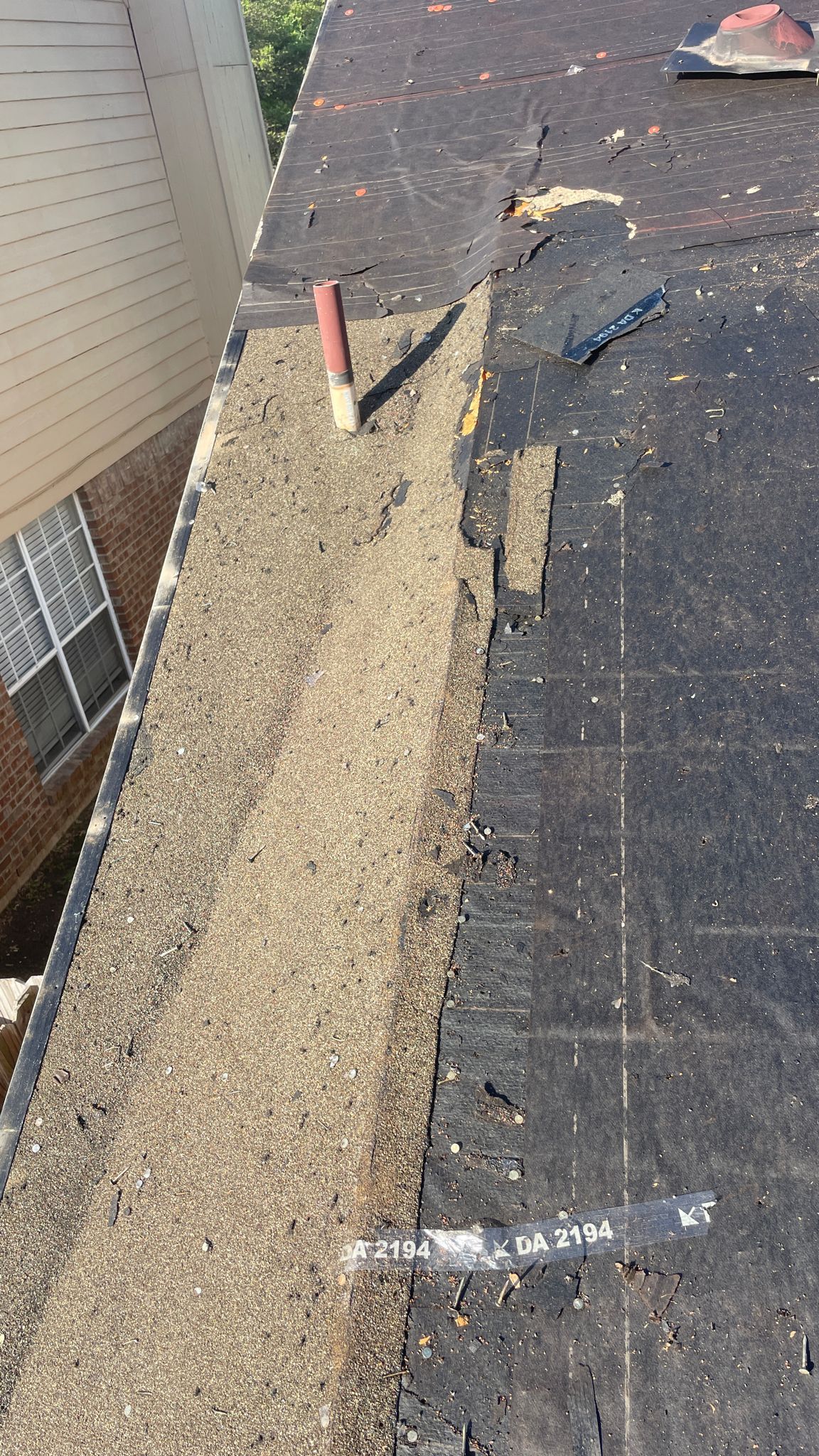 Close-up view of a roof edge, showing missing shingles and exposed underlayment.