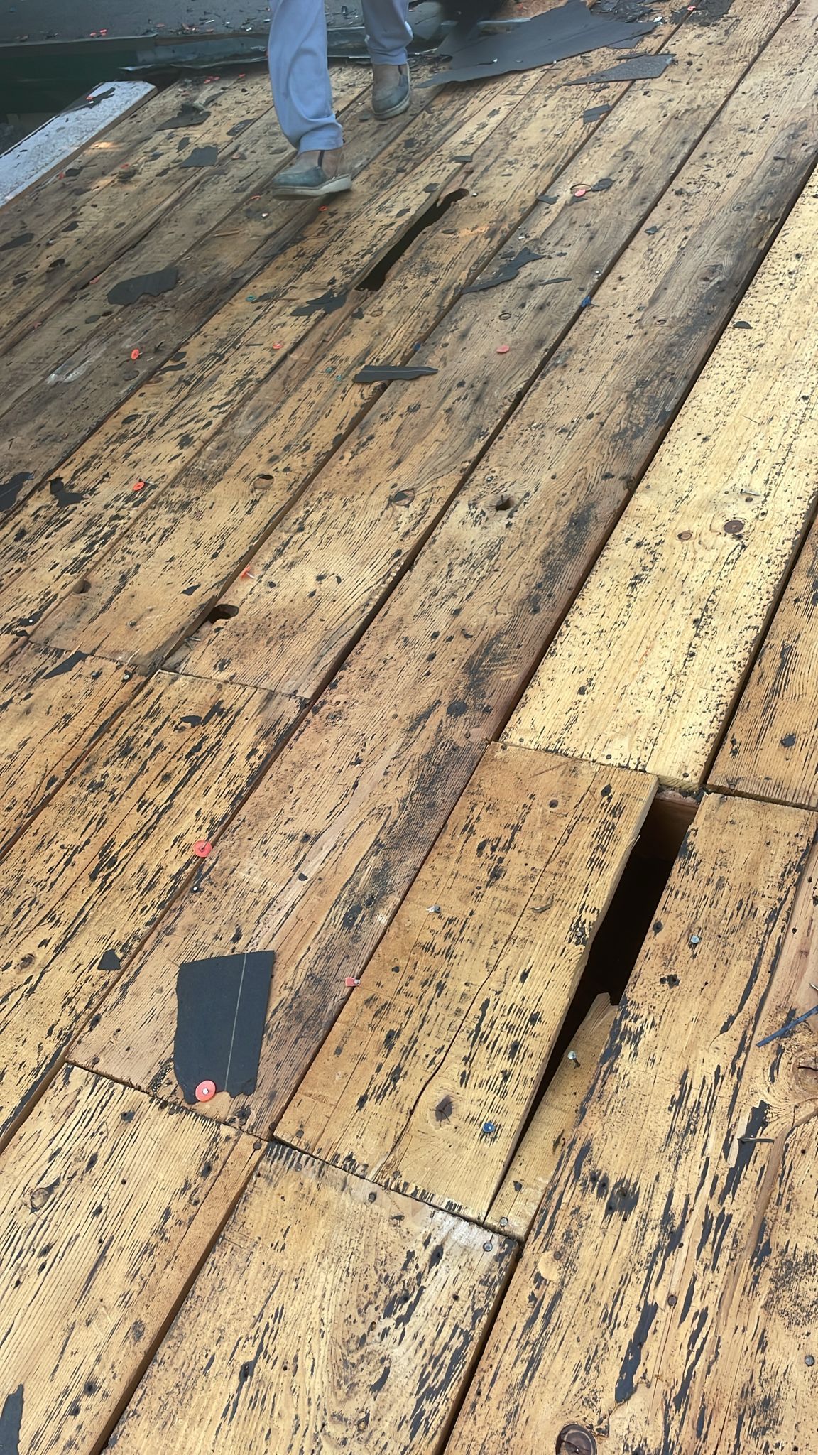Person standing on weathered wooden planks, some darkened.
