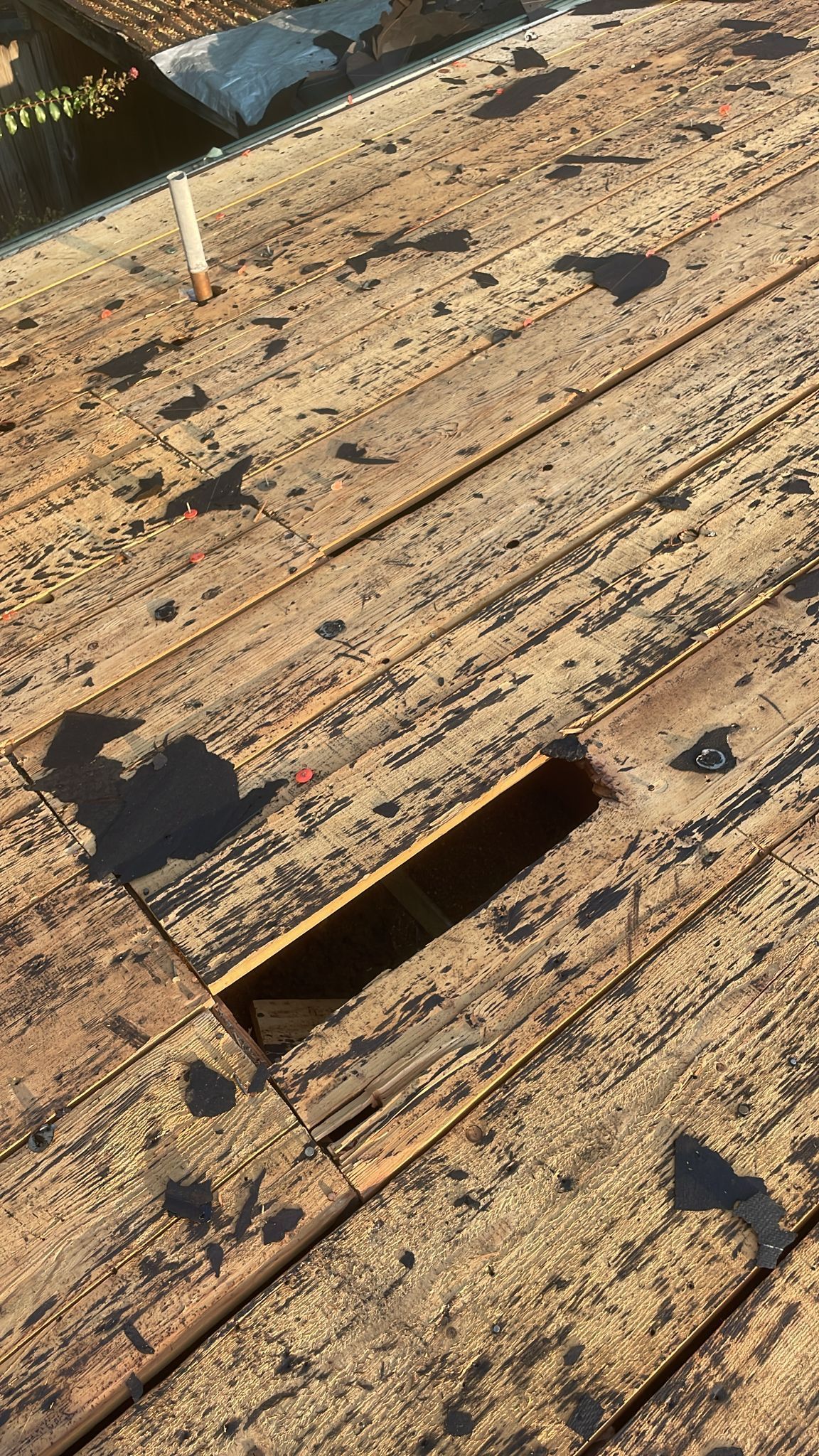 Wooden deck with a rectangular cutout; weathered and worn, with dark spots.