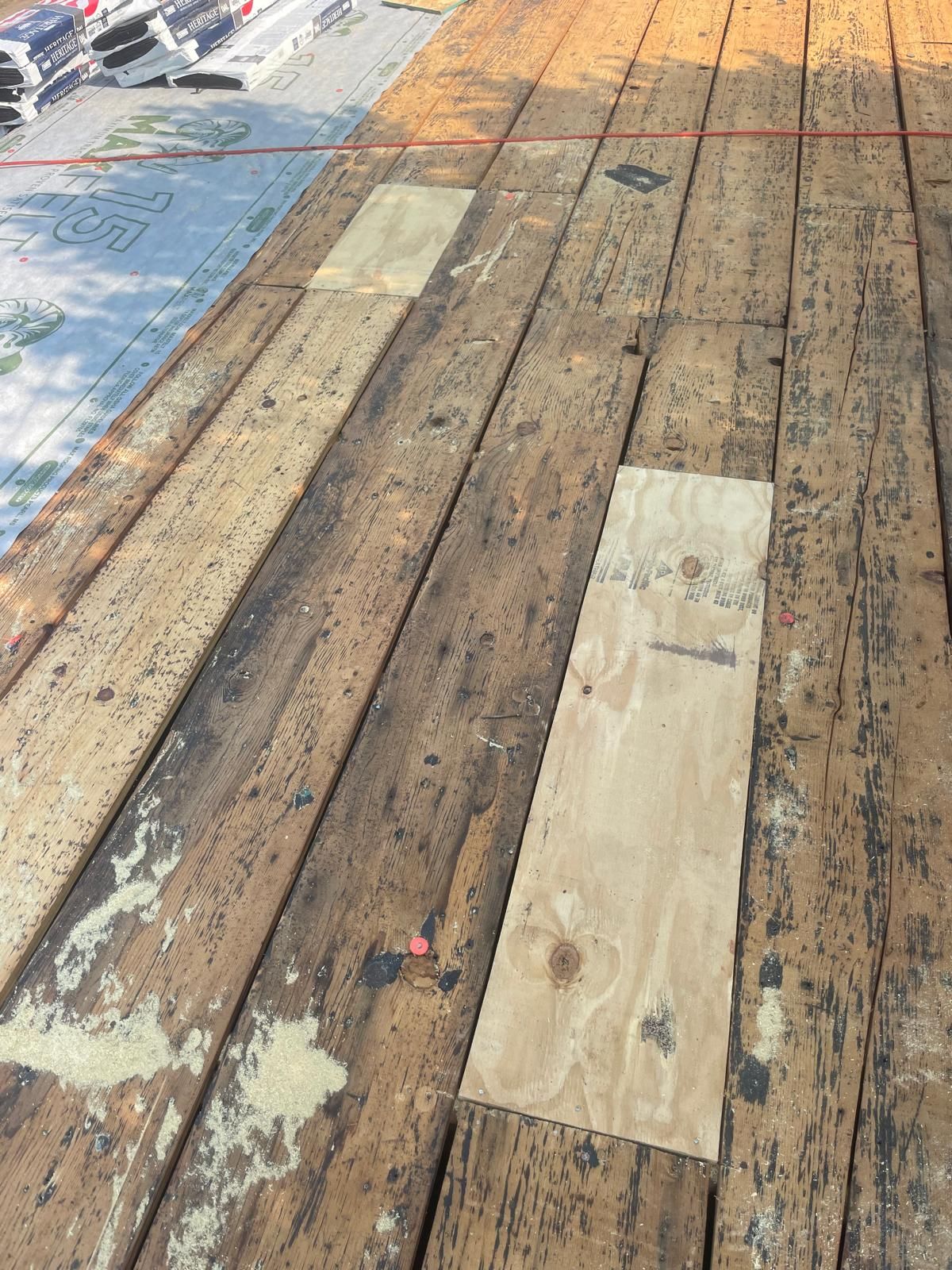 Wooden roof deck with plywood patches, prepared for new roofing.