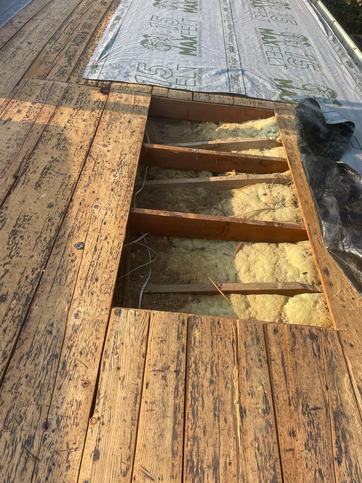 Rotted wooden deck with a rectangular section removed, exposing insulation and supports.