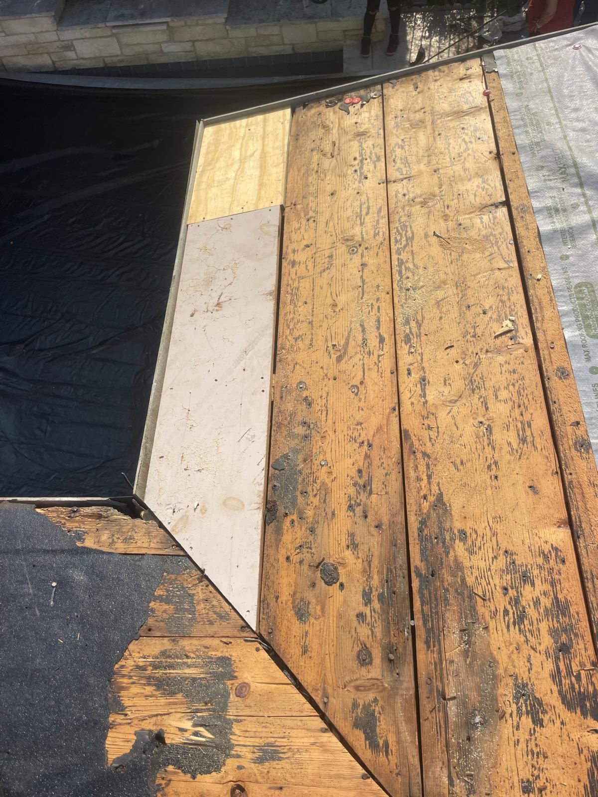 Roofing materials: weathered wood, new plywood, black underlayment.