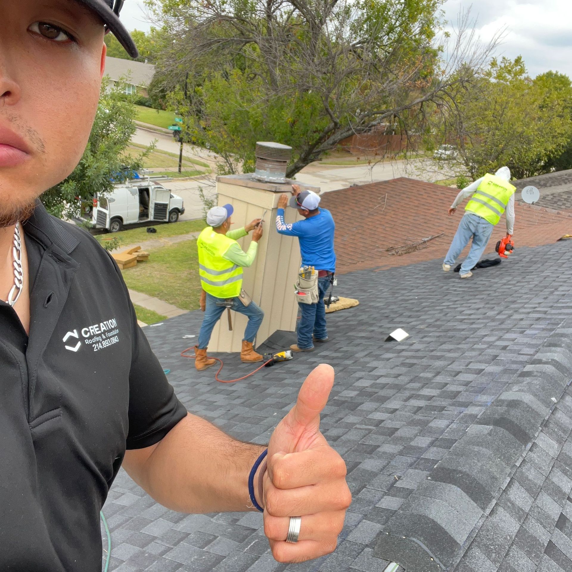 Man on roof gives thumbs up while workers repair chimney.