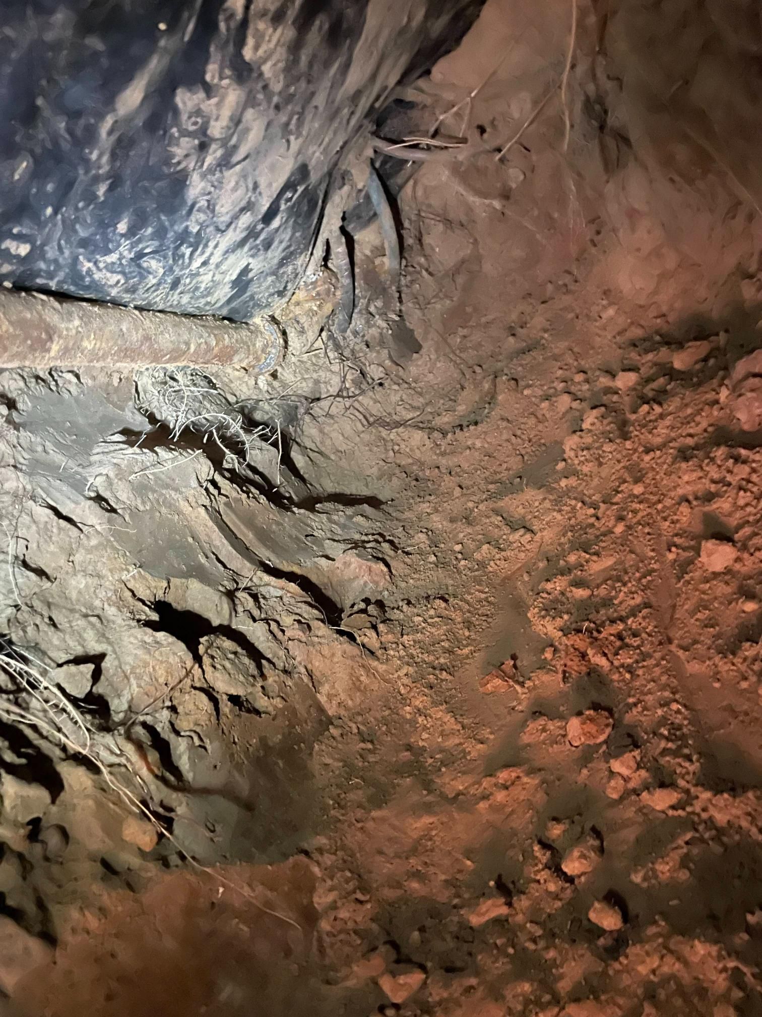 Tunnel interior with dark, possibly wet, walls and dirt floor.