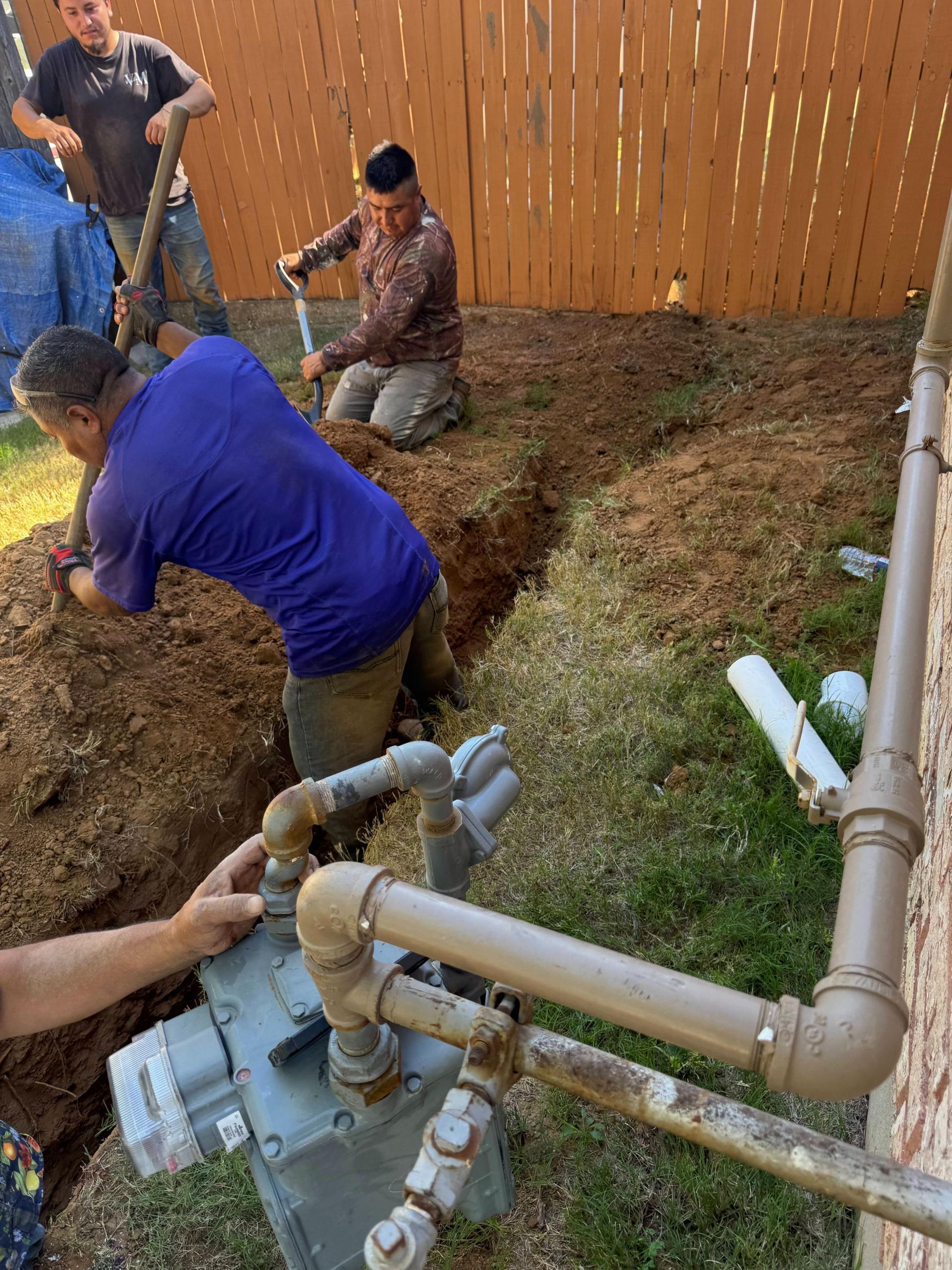 Men dig trench near gas meter and piping.