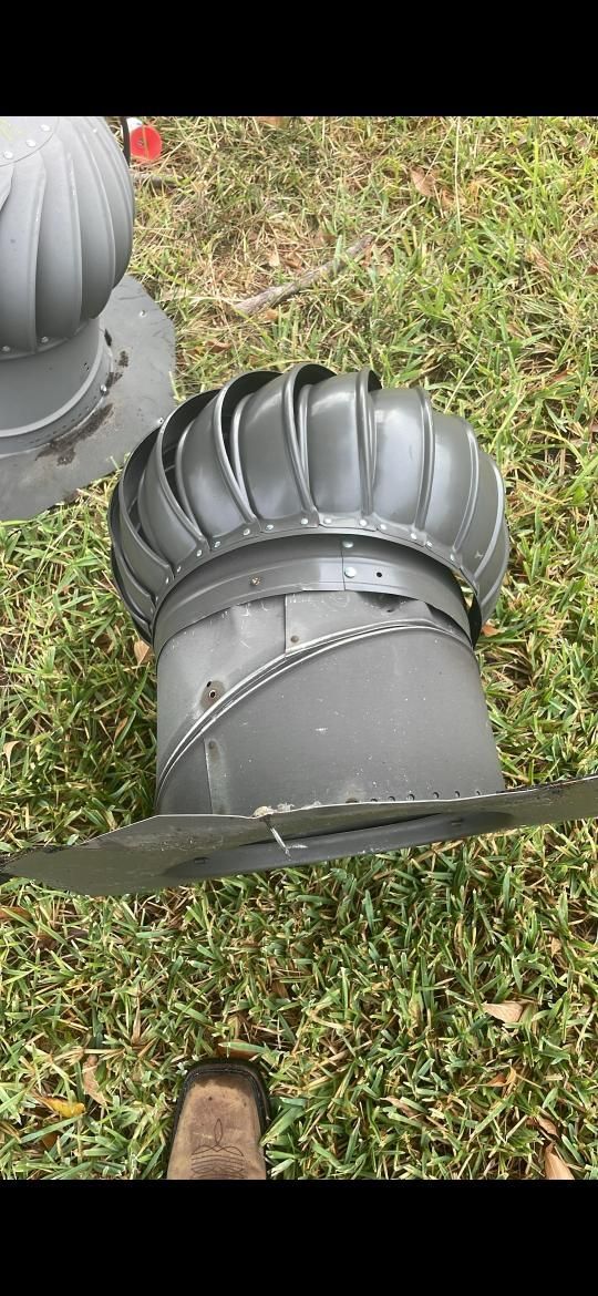 Two gray metal turbine roof vents on grass.