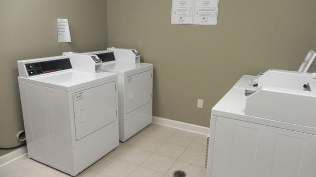 Two white washers and dryers are in a laundry room.