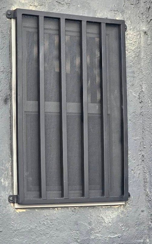 Black security bars on a window in a gray concrete wall.
