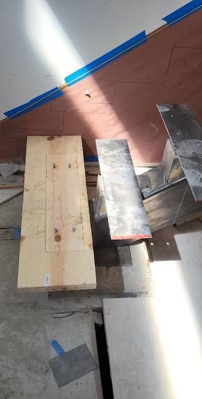 Wooden planks and tiles on a construction site. Blue tape, sunlight, and insulation visible.